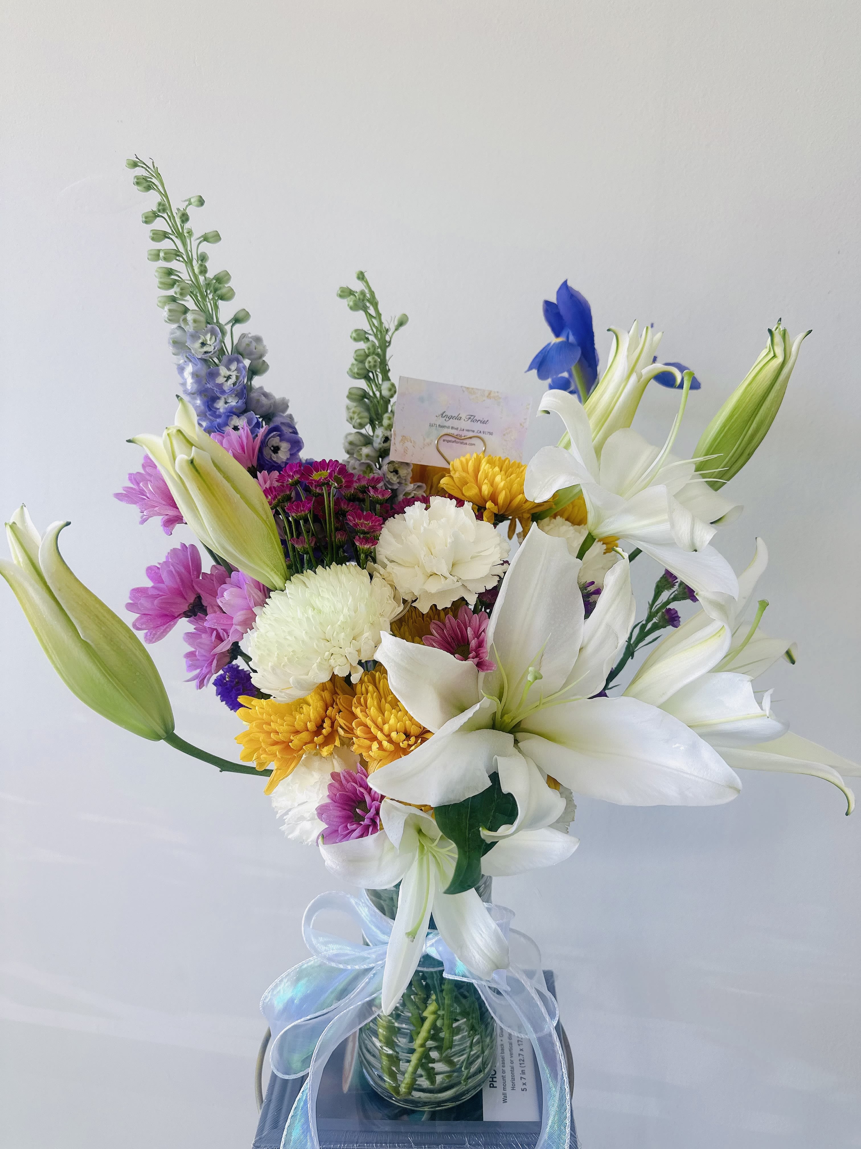 Mixed bouquet with white lilies, chrysanthemums, and purple flowers in a glass vase