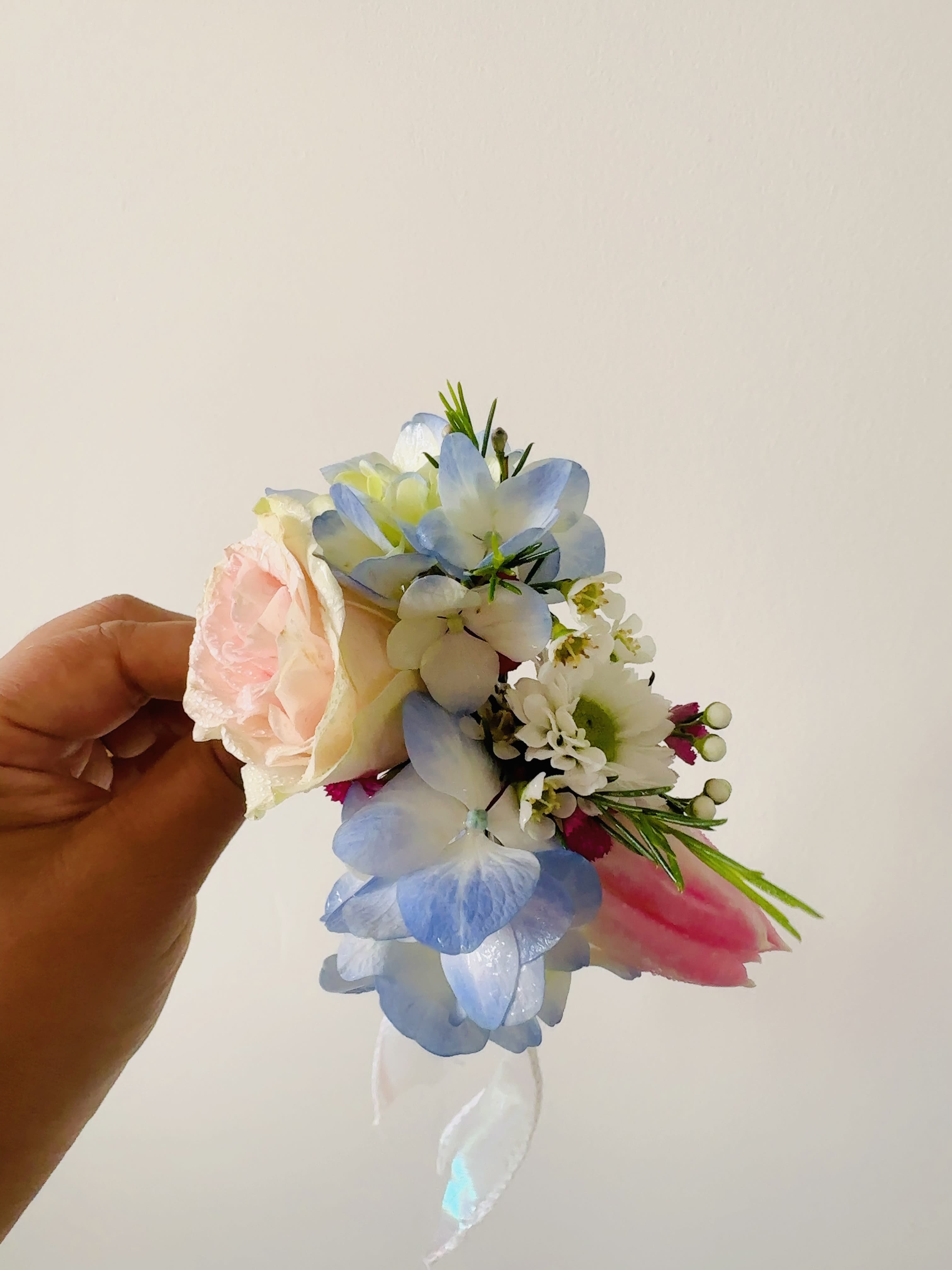 Handheld corsage with a pale pink rose and blue-white flowers
