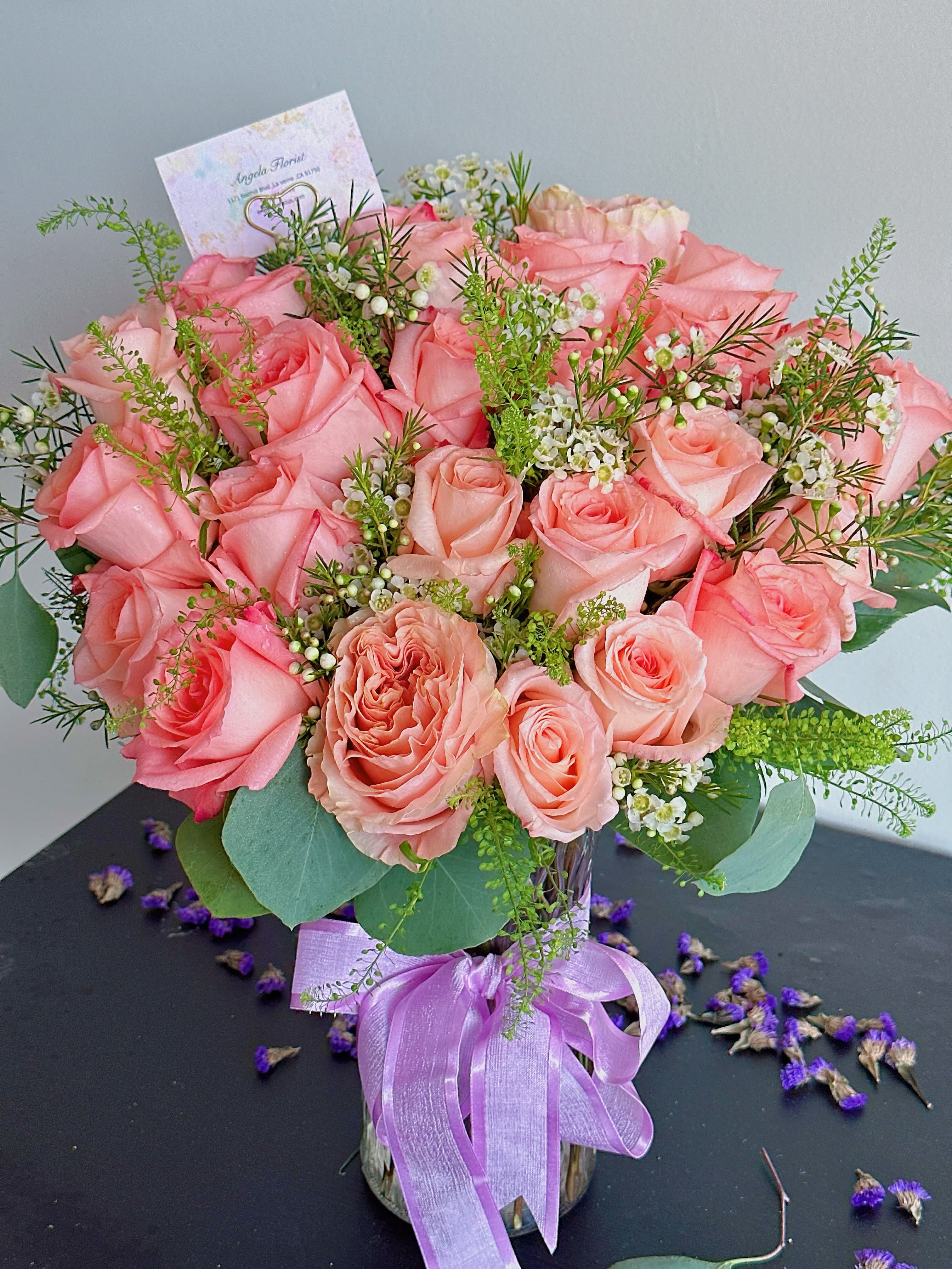 Pink rose bouquet in a glass vase with a lavender ribbon