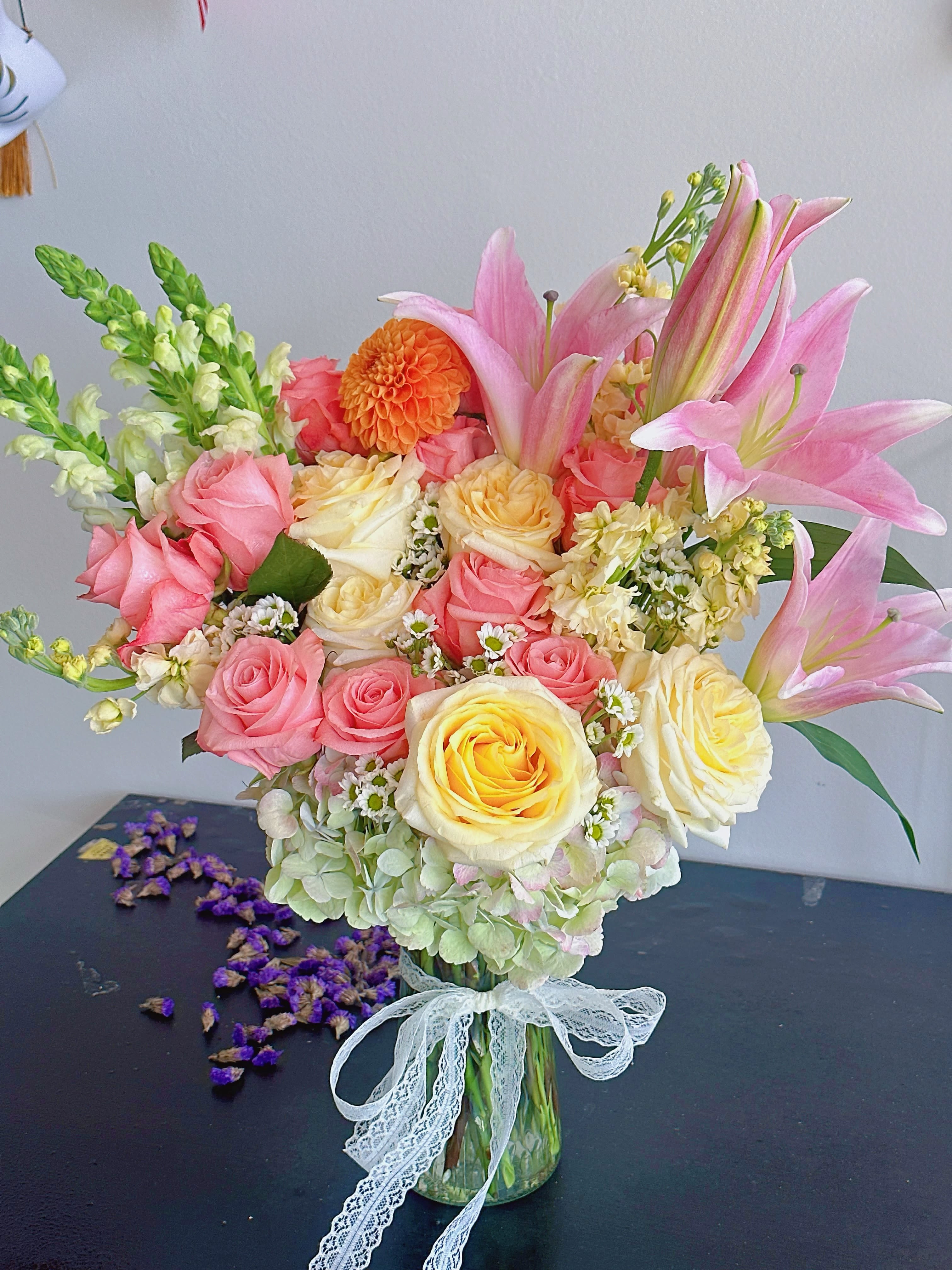 Bouquet of pink and yellow roses with pink lilies in a glass vase