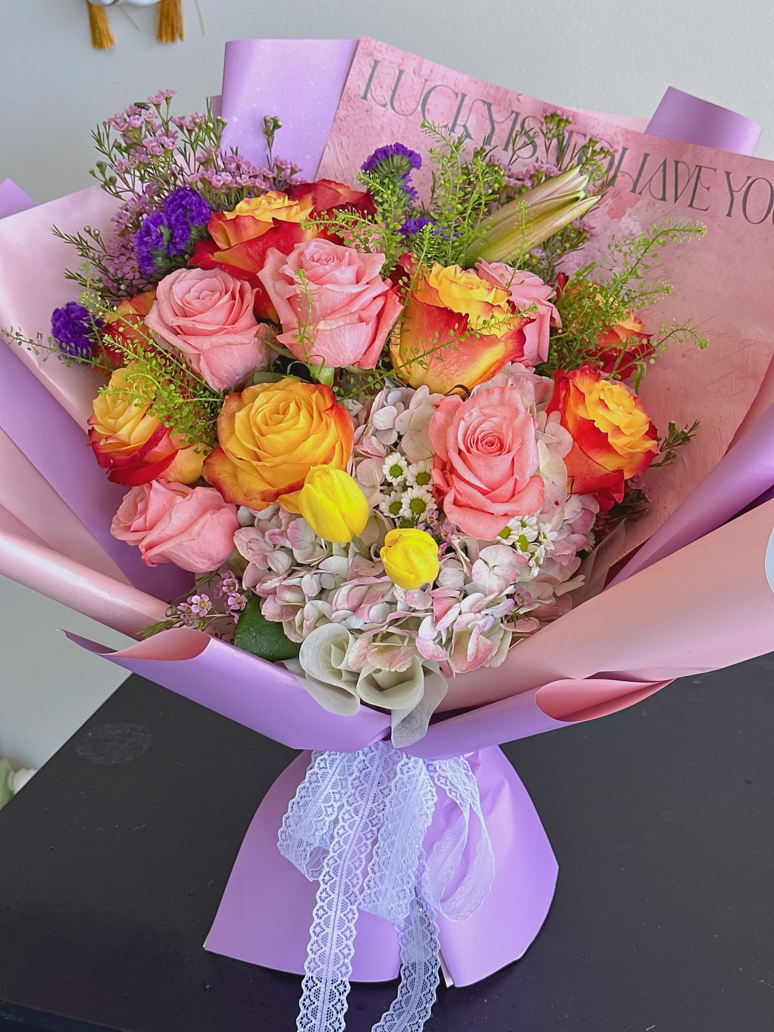 Bouquet of pink and yellow roses wrapped in lavender paper