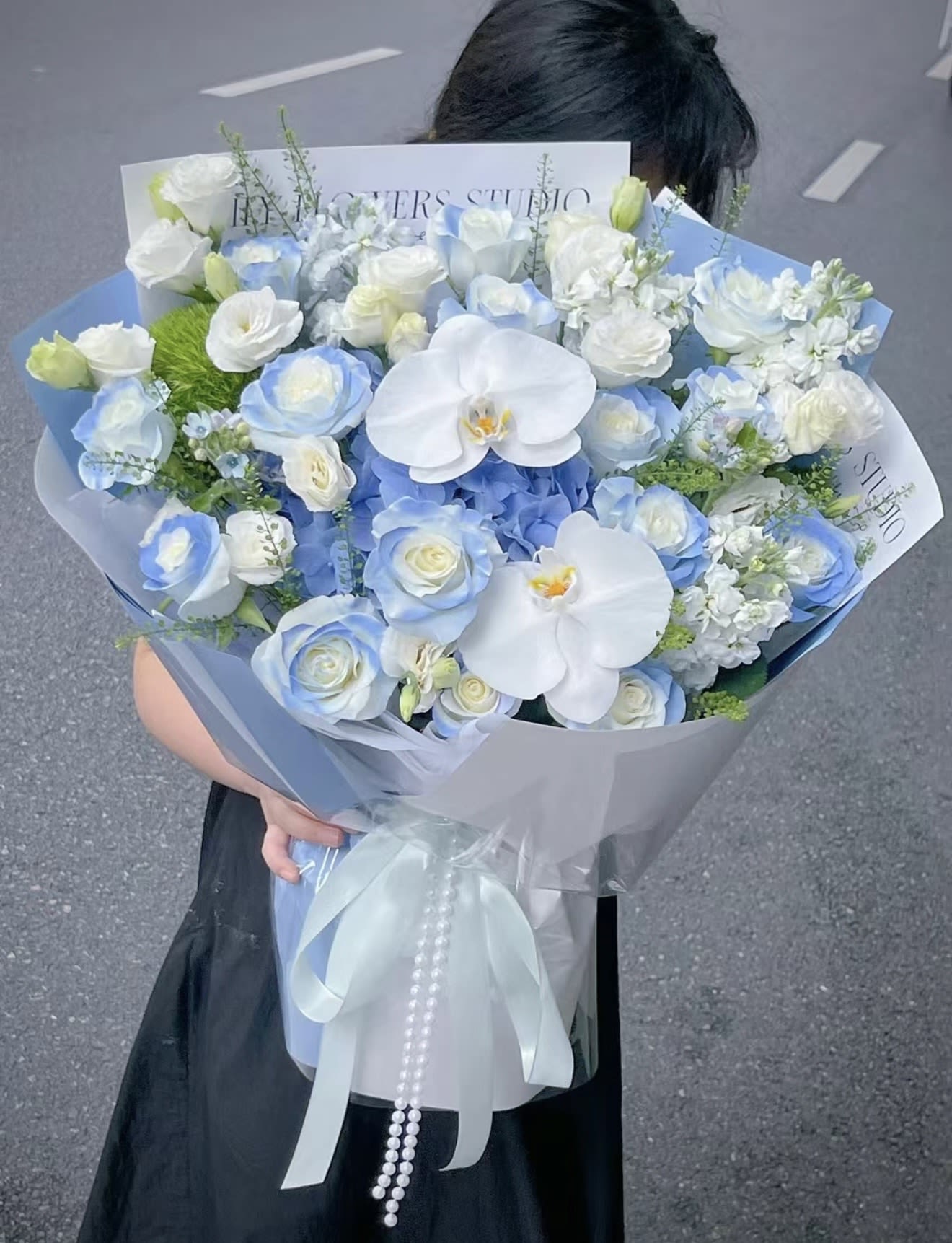 Blue Whisper Bouquet - A dreamy Korean-style bouquet featuring soft blue and white roses, elegant white orchids, hydrangeas, and delicate seasonal blooms. Wrapped in premium layered paper with satin ribbon details, this bouquet is designed to create a luxurious and romantic statement for birthdays, graduations, anniversaries, or special celebrations.   Elegant • Romantic • Luxury Korean Style  Available for pickup and local delivery