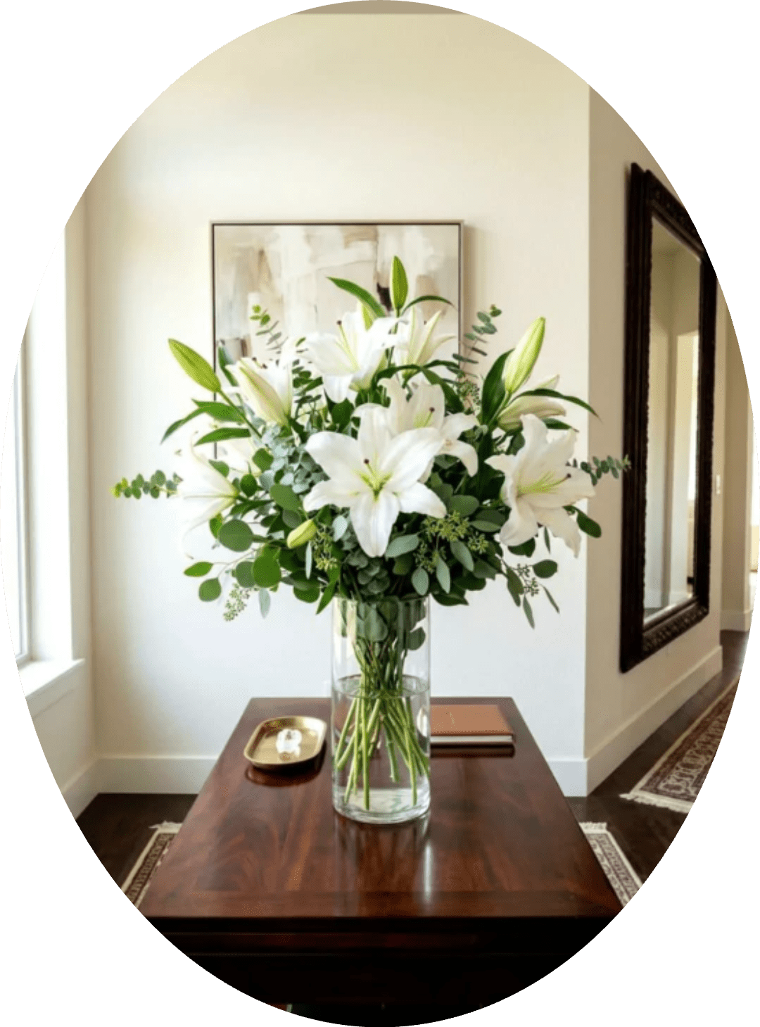Canelones - A cluster of large white lilies arranged upright in a tall clear glass vase creates a fresh, serene bouquet perfect for a sympathy arrangement, wedding décor, or a calm everyday display. The white-and-green palette reads formal and refined, so the person you're thinking of will feel comforted and seen by the quiet elegance of these blooms.  Open lilies and a few unopened buds rise at varying heights through visible stems and water, surrounded by airy eucalyptus-like foliage and mixed greenery that fill the silhouette without crowding the blooms. The composition is full yet spacious, with broad white petals and soft green accents that suit a mantel, entry table, or chapel setting.  This arrangement makes a simple, meaningful gift for memorial moments, understated celebrations, or to bring refined tranquility to a home. Delivered in the tall clear glass vase shown, it arrives ready to display; refresh the water every few days and trim stems as needed to help the lilies open fully and last longer.