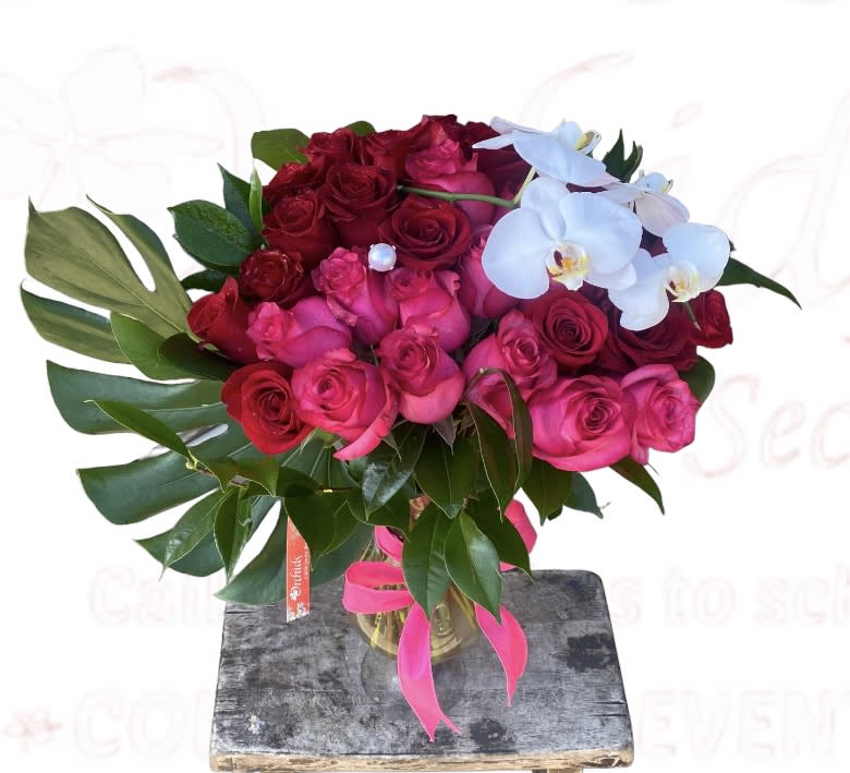 Bouquet of red and pink roses with white orchids in a glass vase