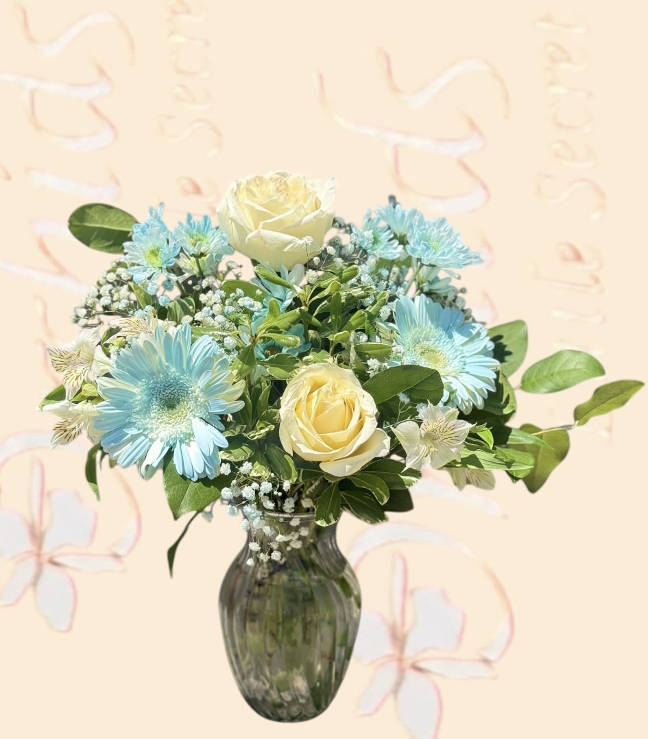 Blue daisies and cream roses arranged in a glass vase