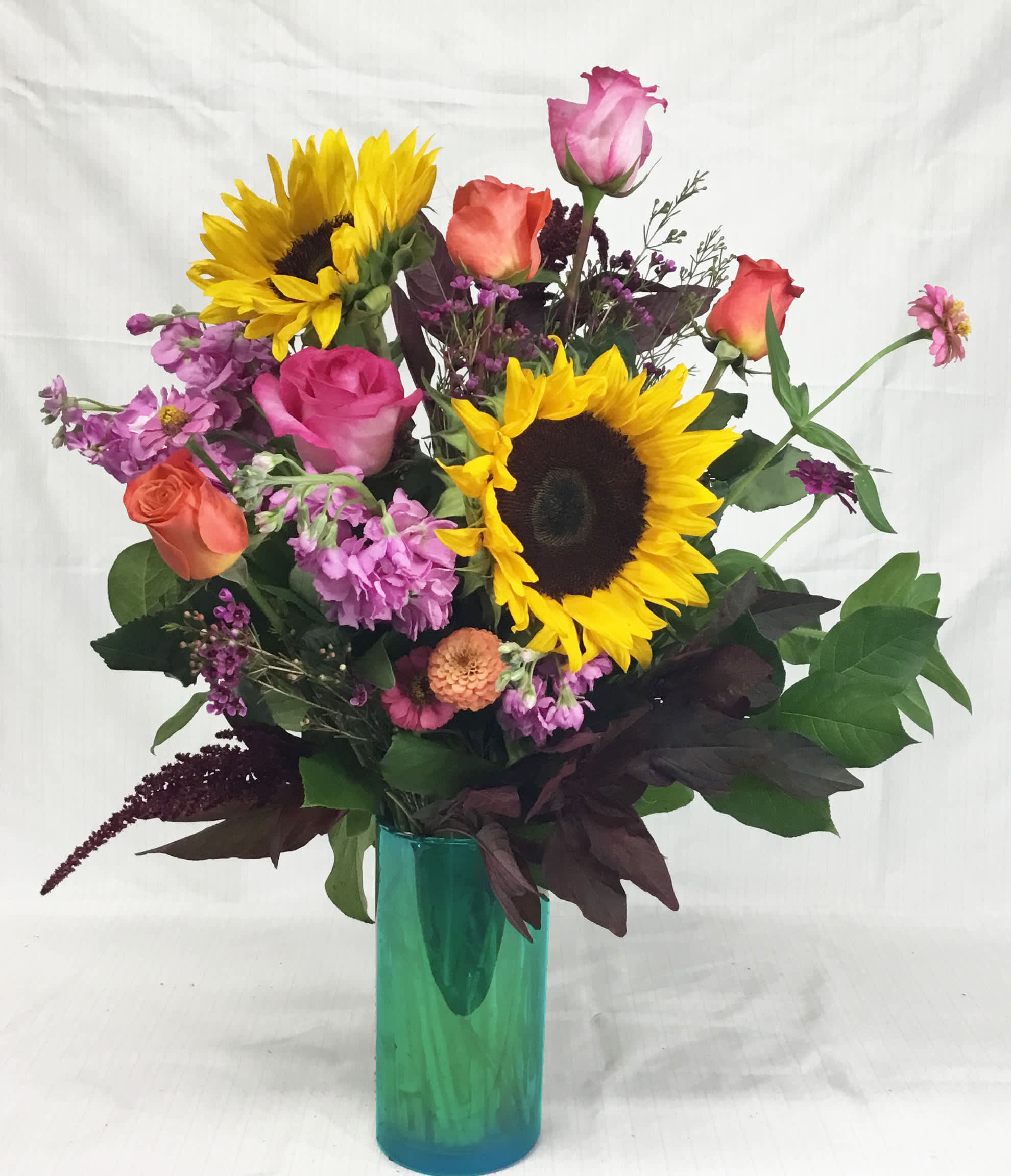 Endless Summer - Assorted Summer blooms in a pretty aqua blue vase.
