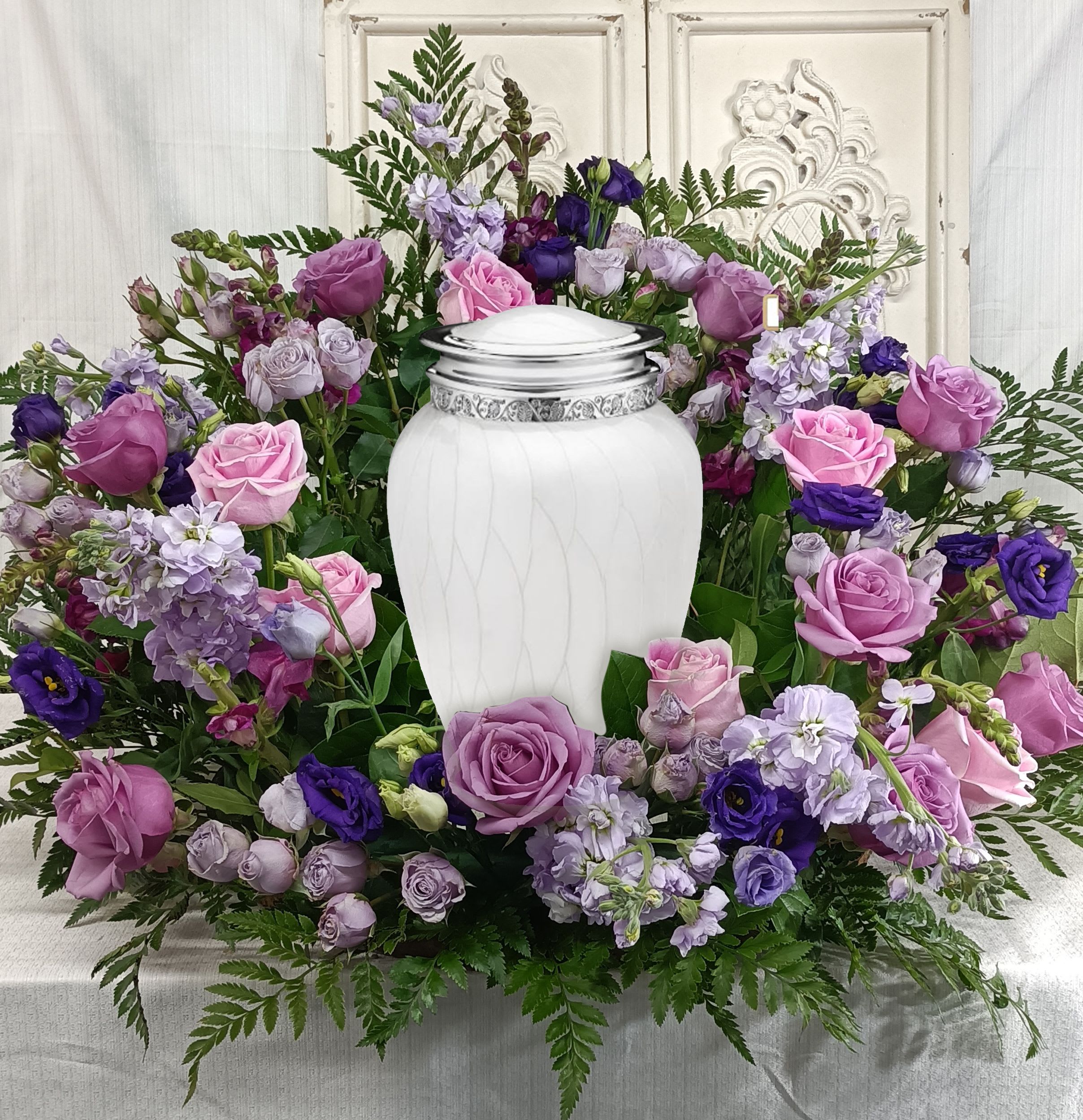 Purple and pink rose funeral wreath with a white urn centerpiece
