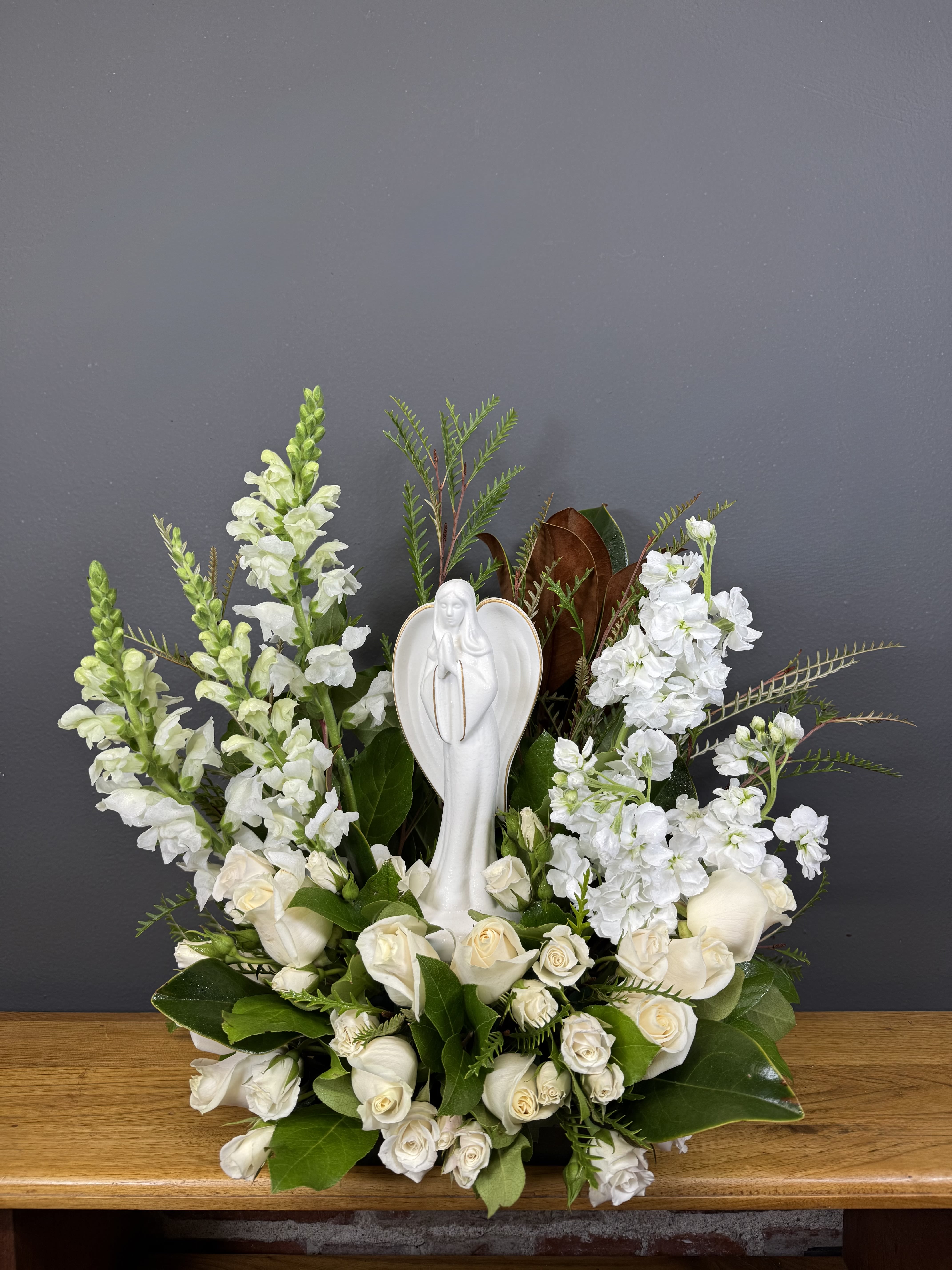 White floral arrangement with a religious statue centerpiece