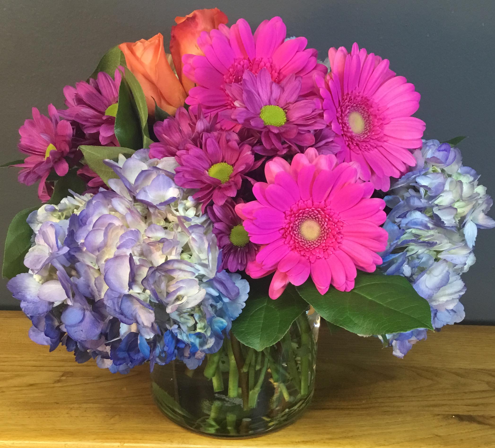 Summer Celebration - Assorted Brightly colored Blooms in a light Lavendar Vase