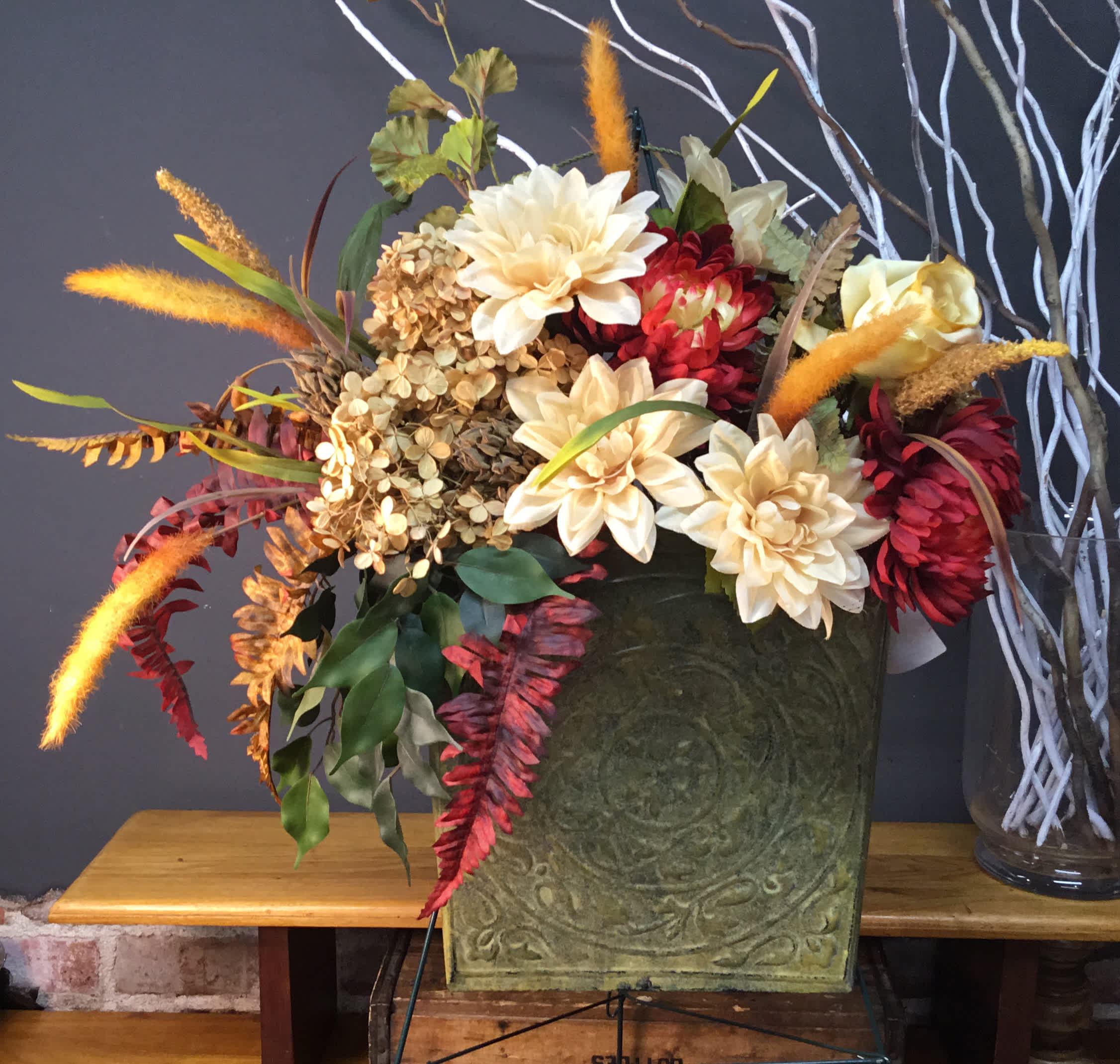 Autumn floral arrangement with cream and red blooms in a green container