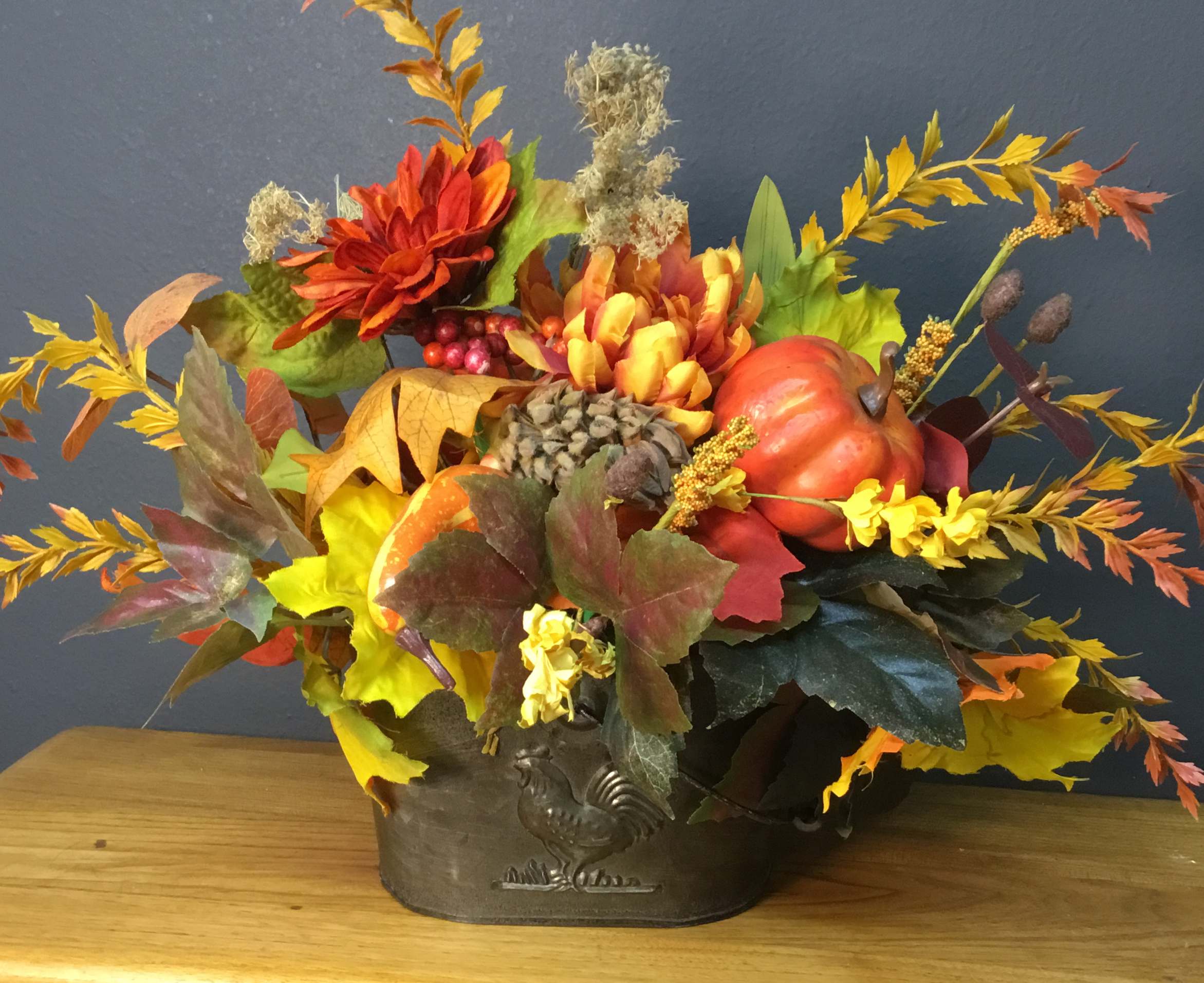 Autumn floral arrangement with pumpkins in a metal container