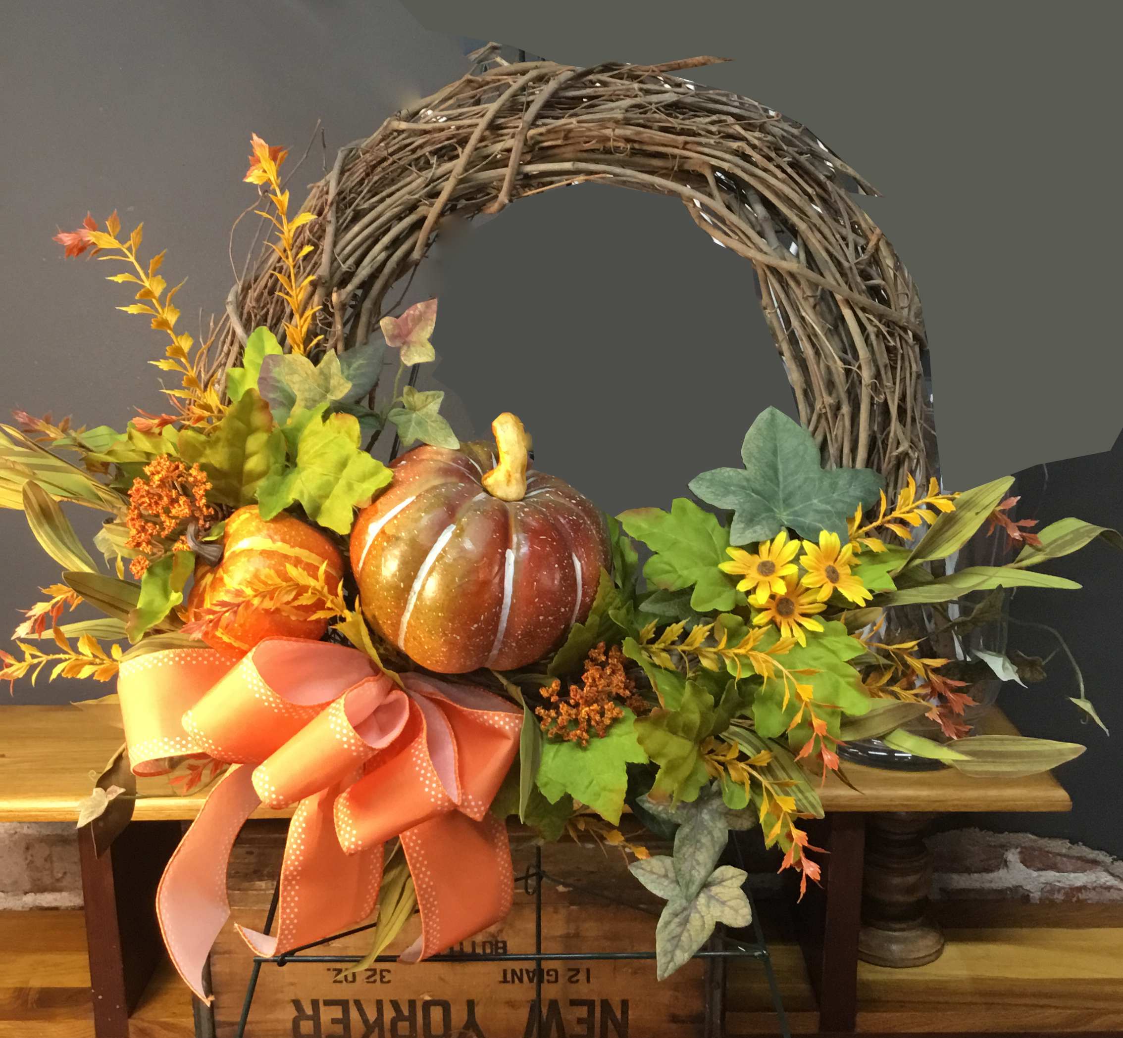 Fall wreath with pumpkins, yellow flowers, and a large orange ribbon