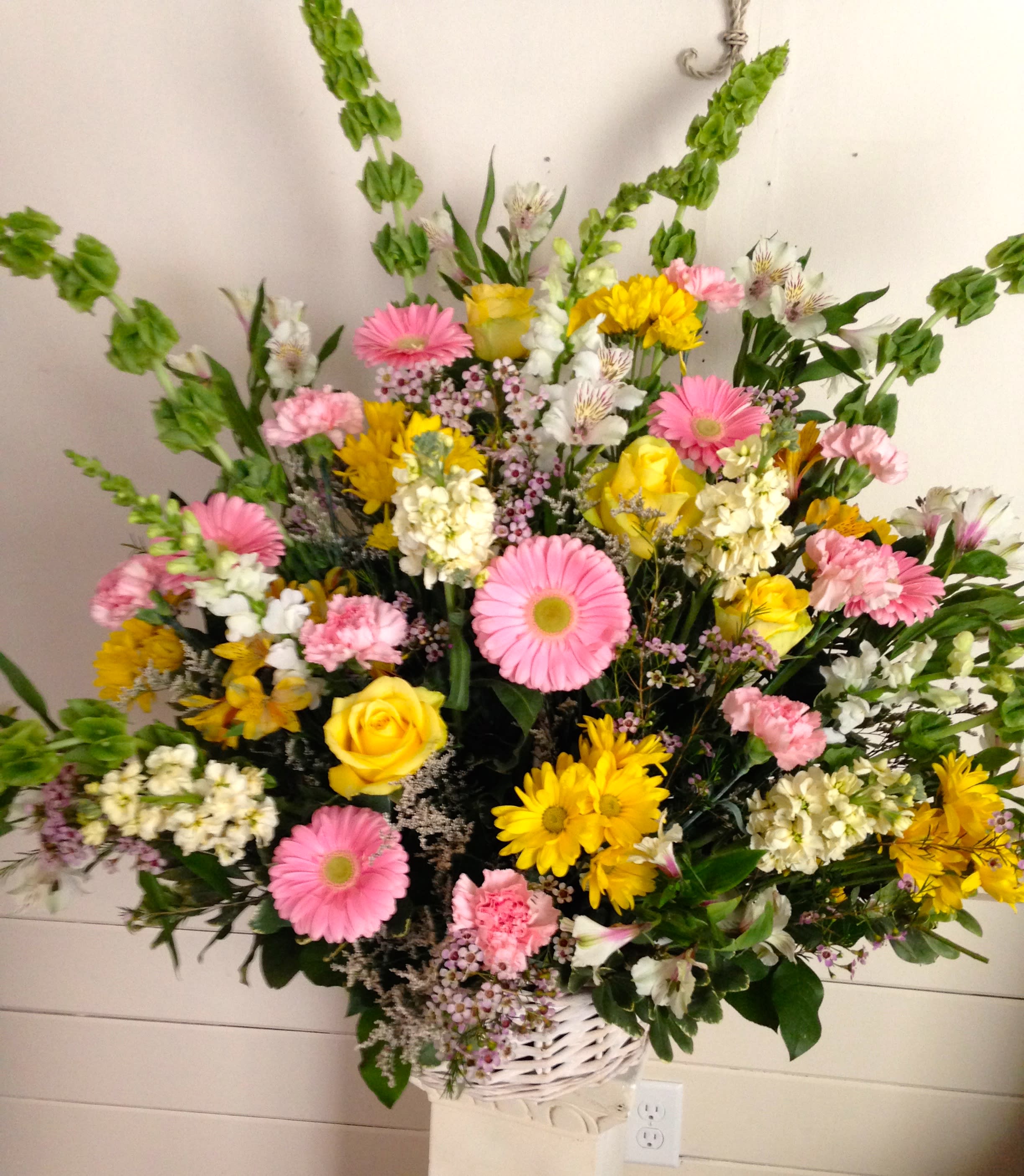 Mixed bouquet of pink and yellow flowers in a white basket vase