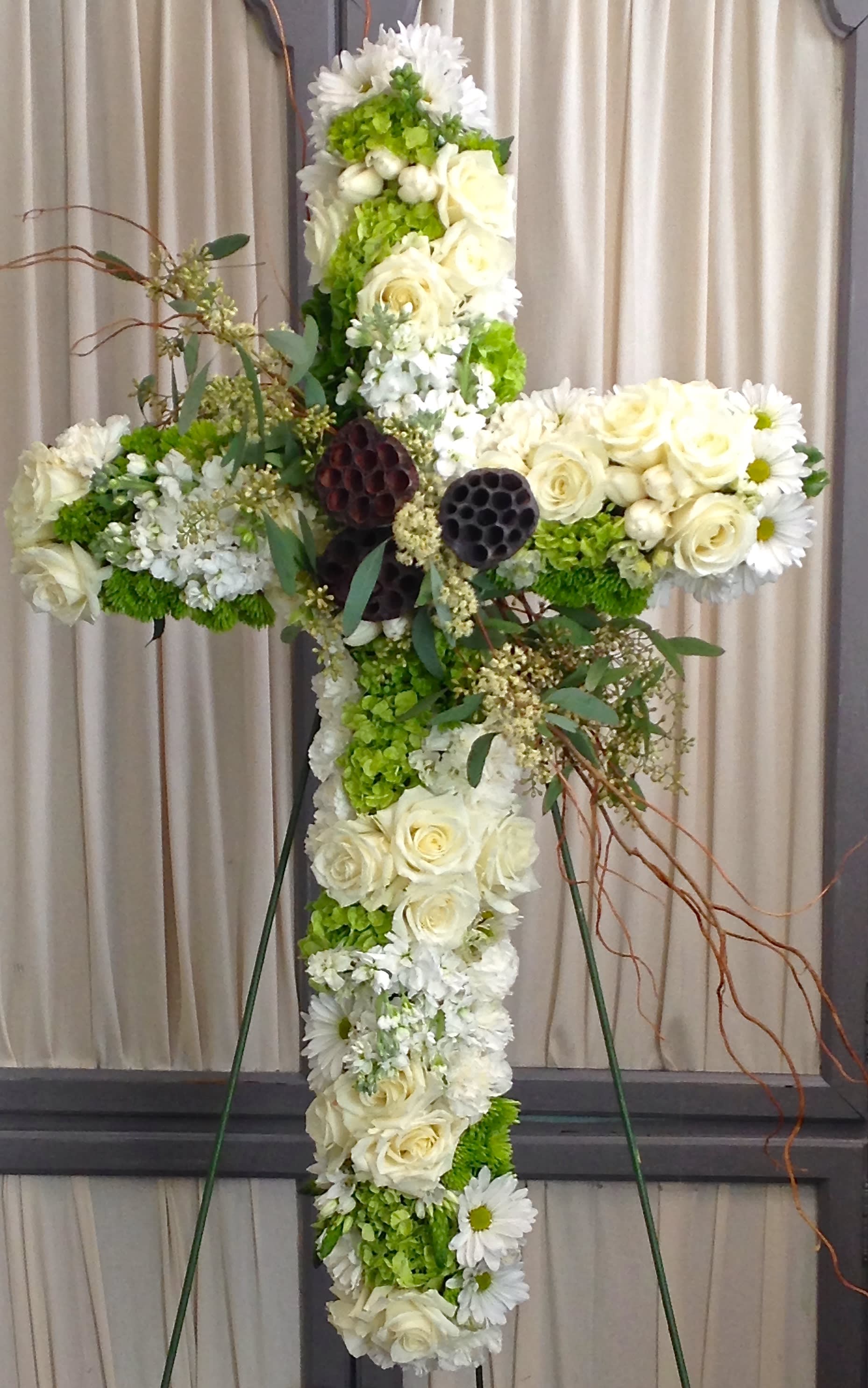 Large floral cross with white roses, daisies, and green hydrangeas