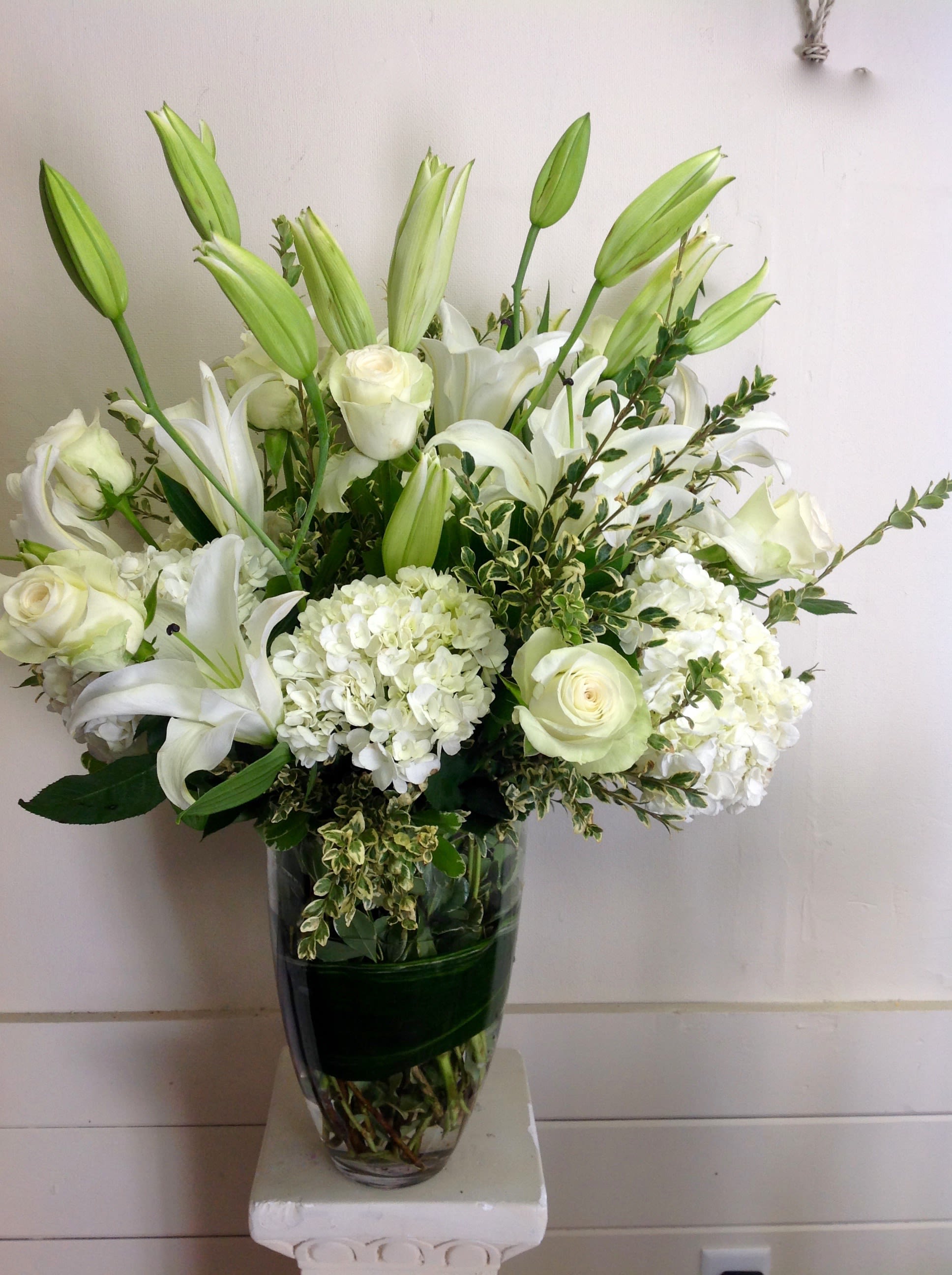 White lilies and roses arranged in a clear glass vase