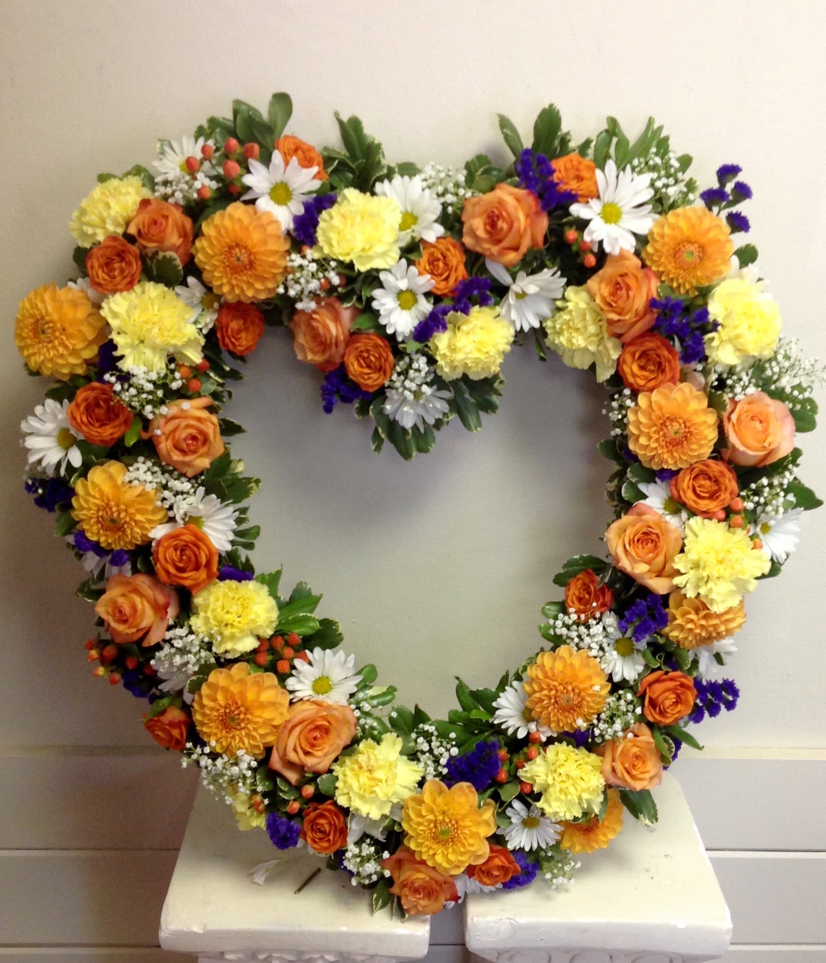 Heart-shaped floral wreath with orange, yellow, white, and purple flowers