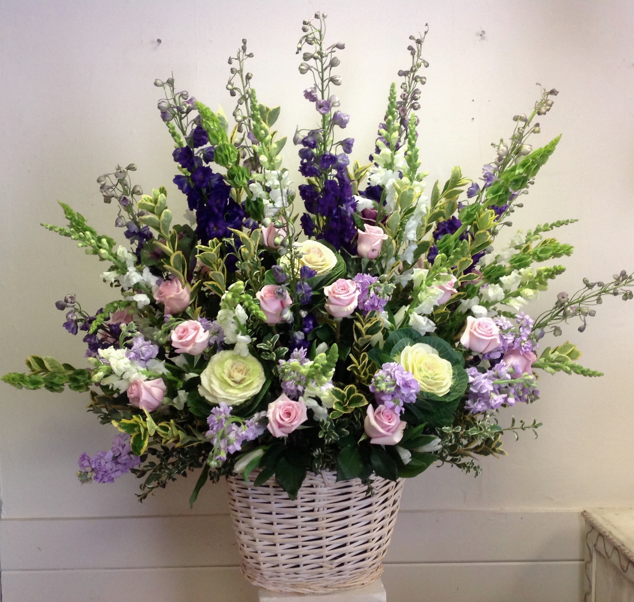 Large basket arrangement of pink and cream roses with purple and white spikes