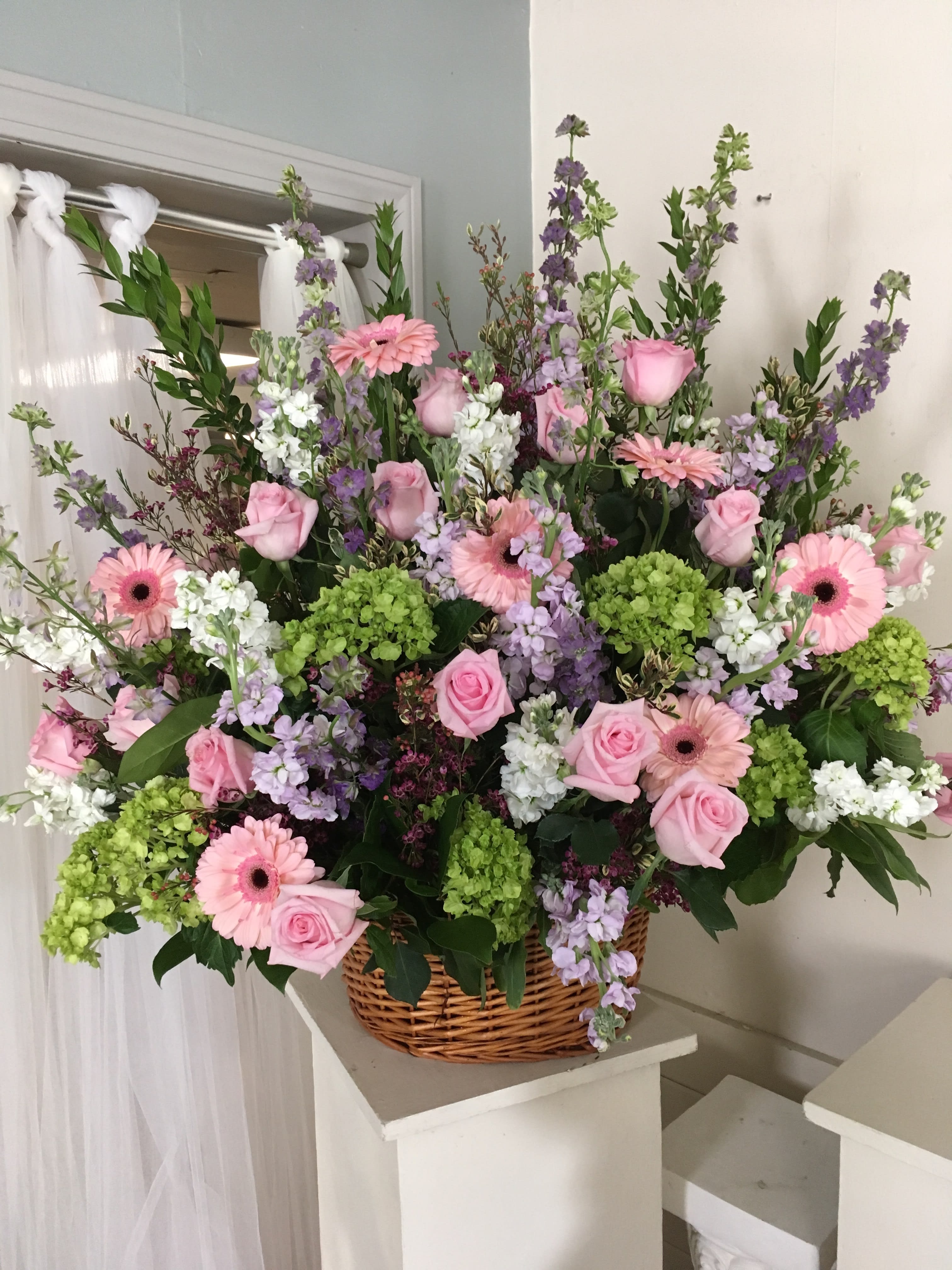 Large basket arrangement of pink roses, gerbera daisies, and purple flowers