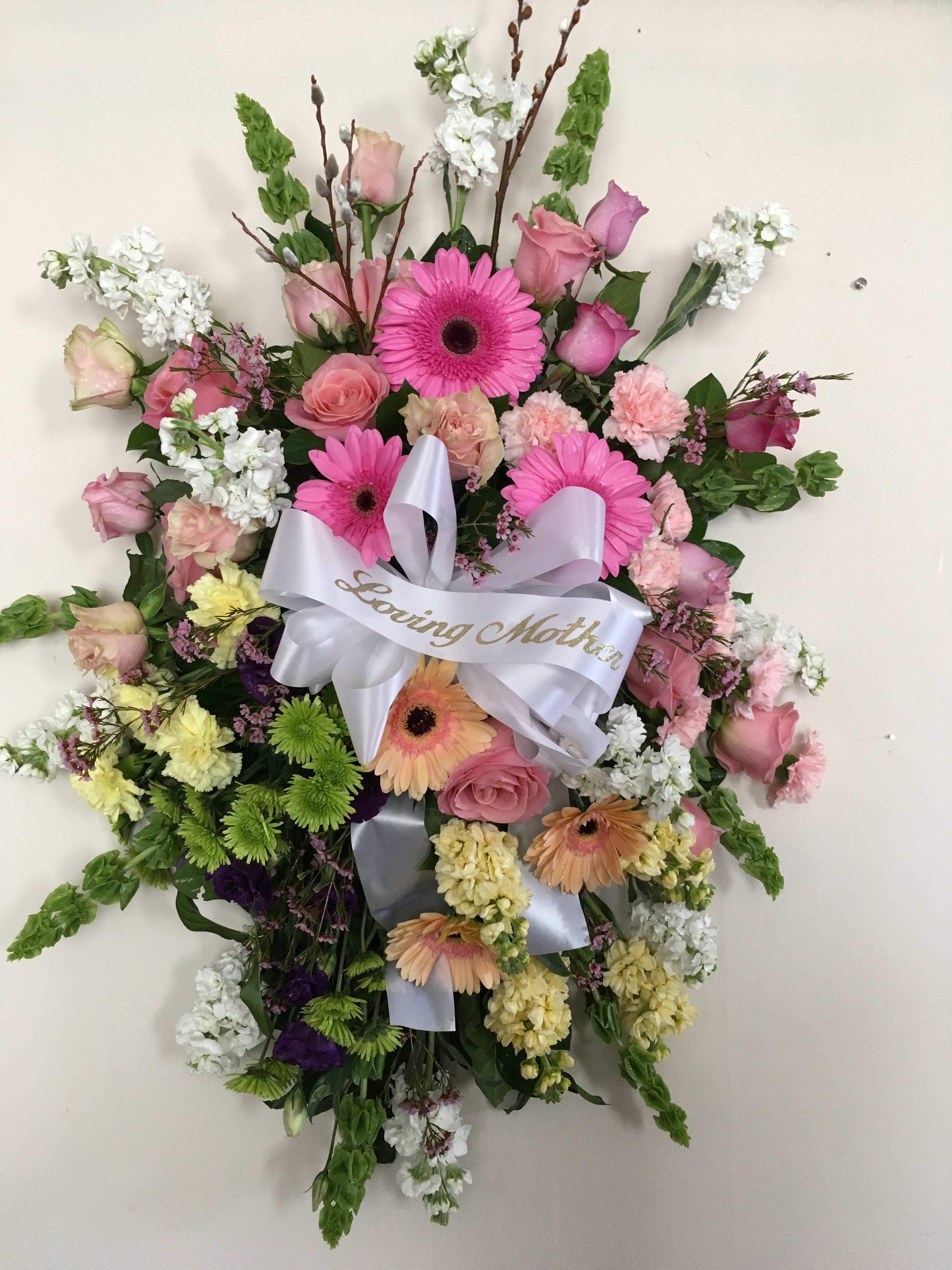 Heart-shaped floral wreath with pink and white flowers and a ribbon