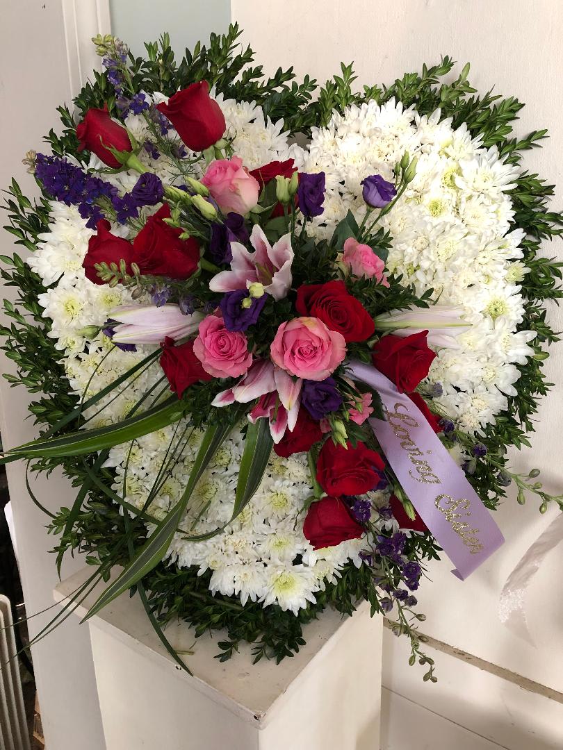 Large floral spray with red and pink roses, white chrysanthemums, and purple accents