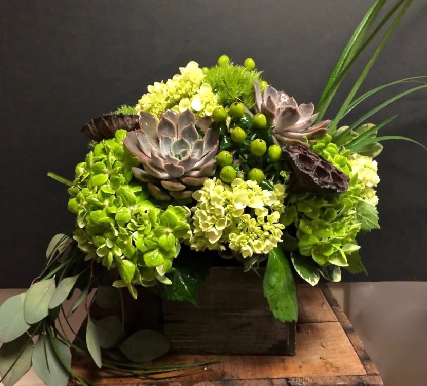 Green floral arrangement with succulents and hydrangeas in a wooden box