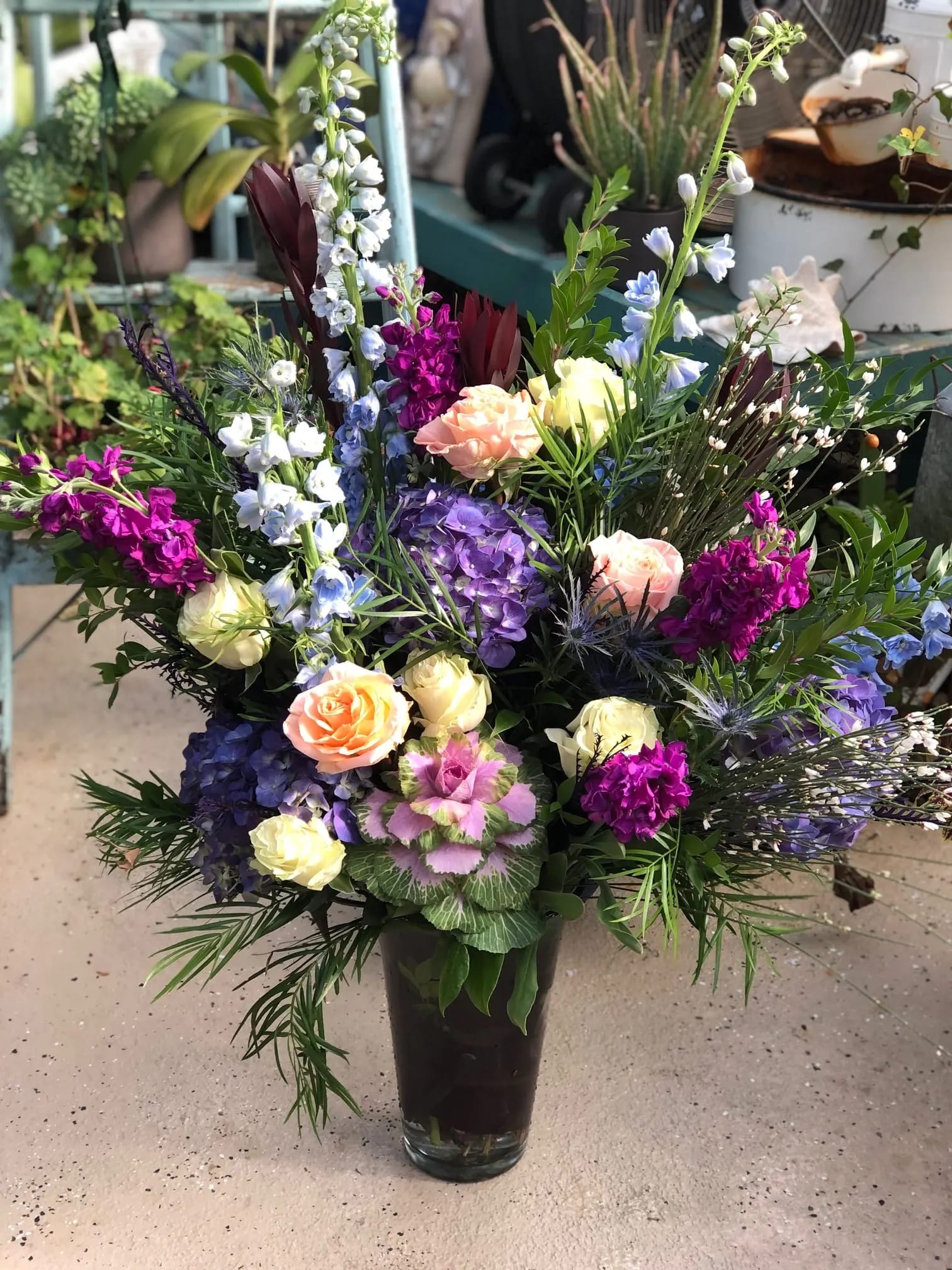 Tall mixed bouquet in a glass vase with roses and purple blooms