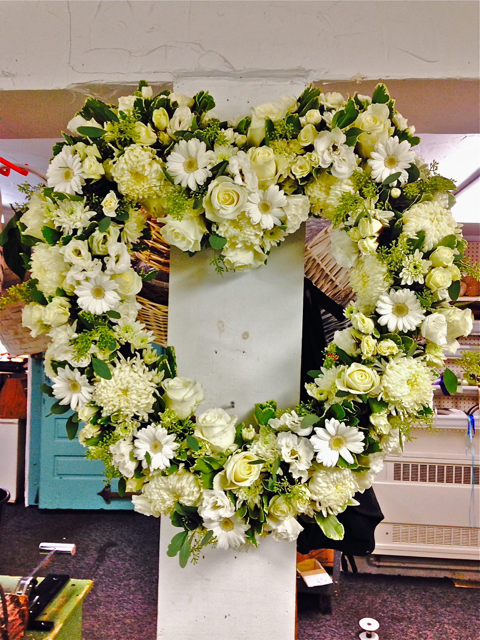 Heart-shaped white floral wreath on a stand