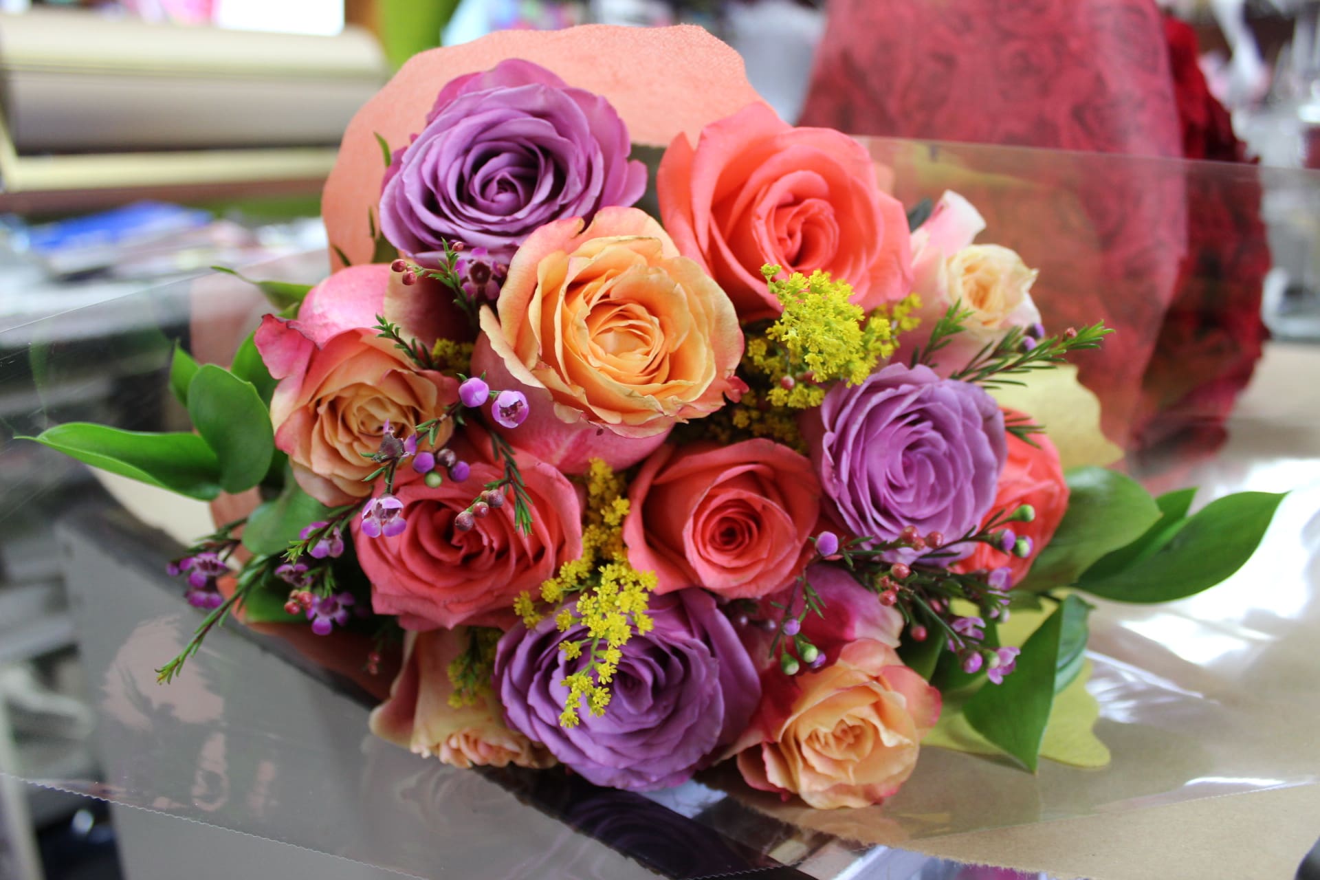 Bouquet of pink, peach, and purple roses with small yellow filler flowers