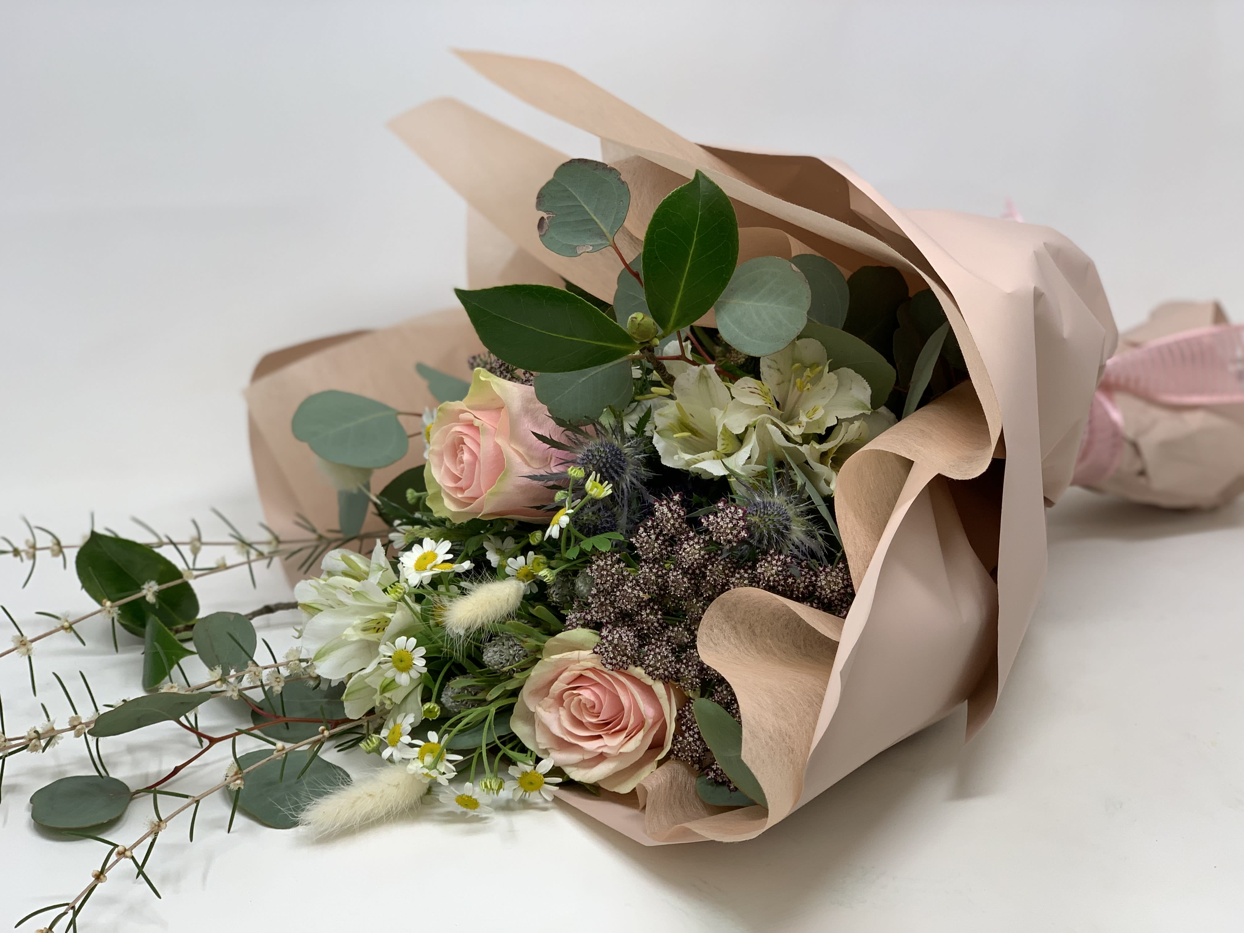 Bouquet of pink roses and white flowers wrapped in blush paper