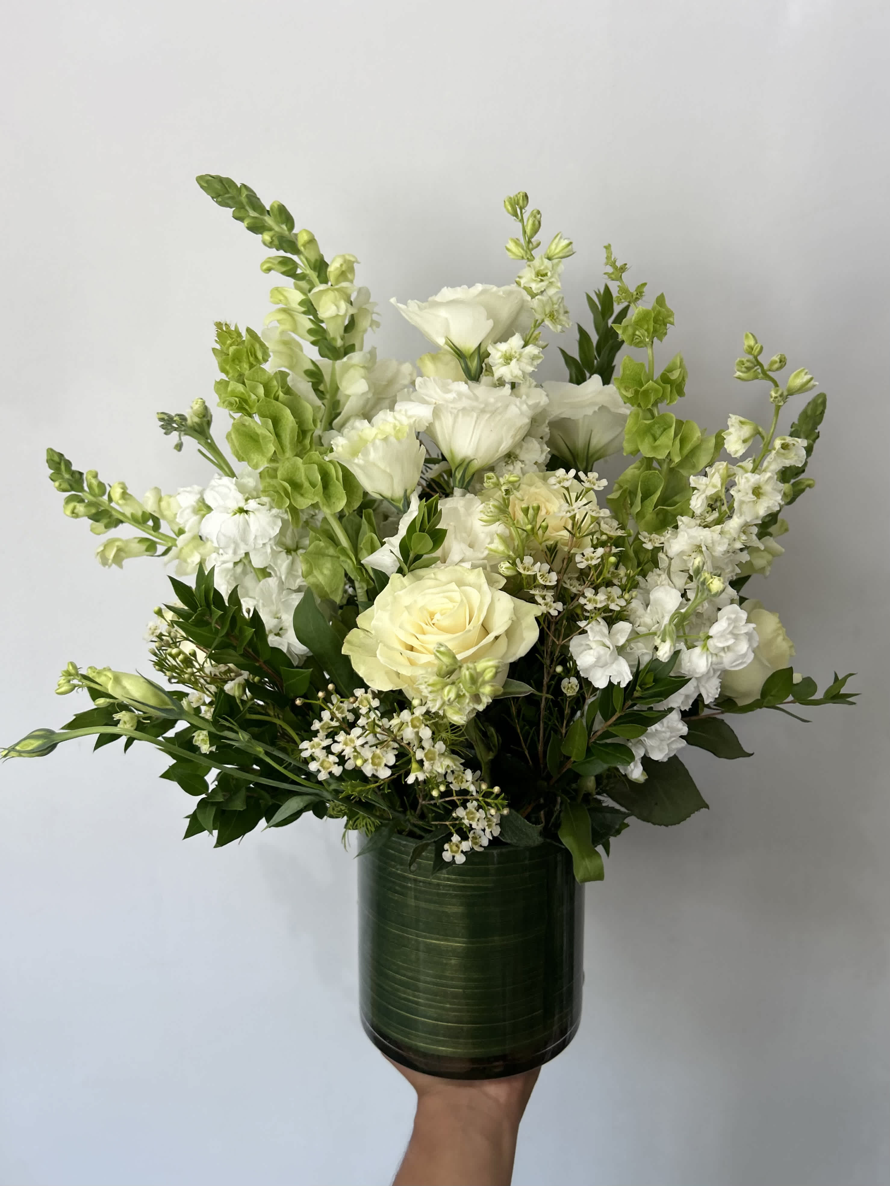 Serenity - Seasonal white flowers arranged with fillers and greens in a vase.