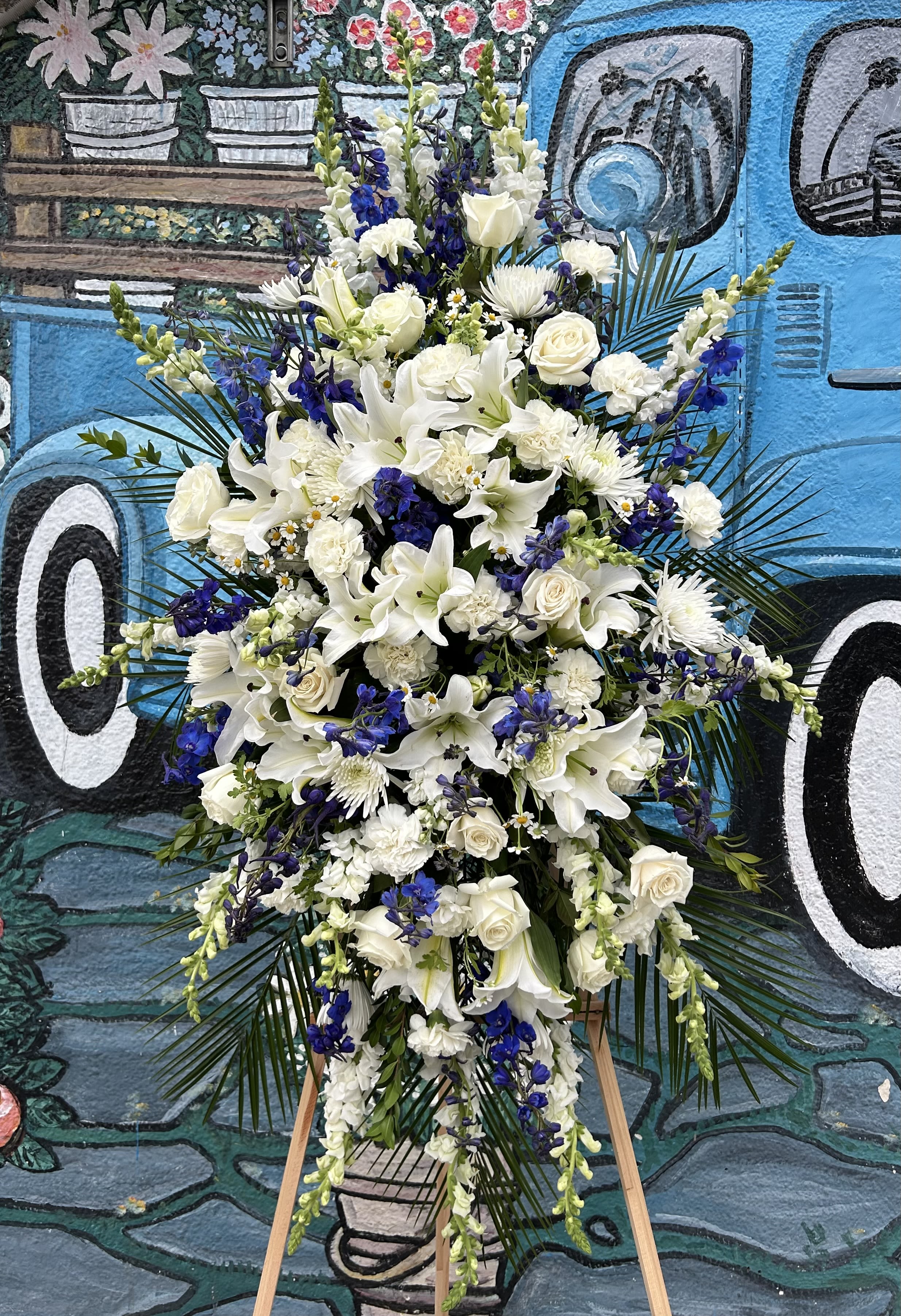 Tall white and blue floral standing spray on an easel