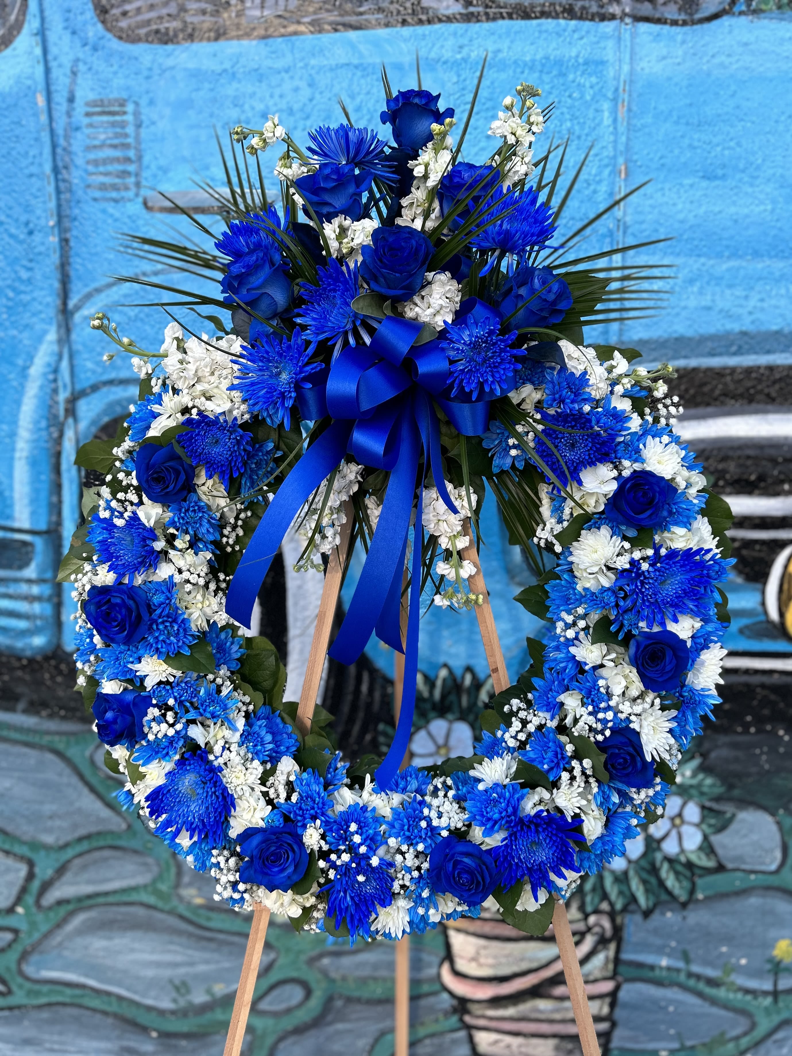 Blue and white floral wreath on a wooden easel with a ribbon bow