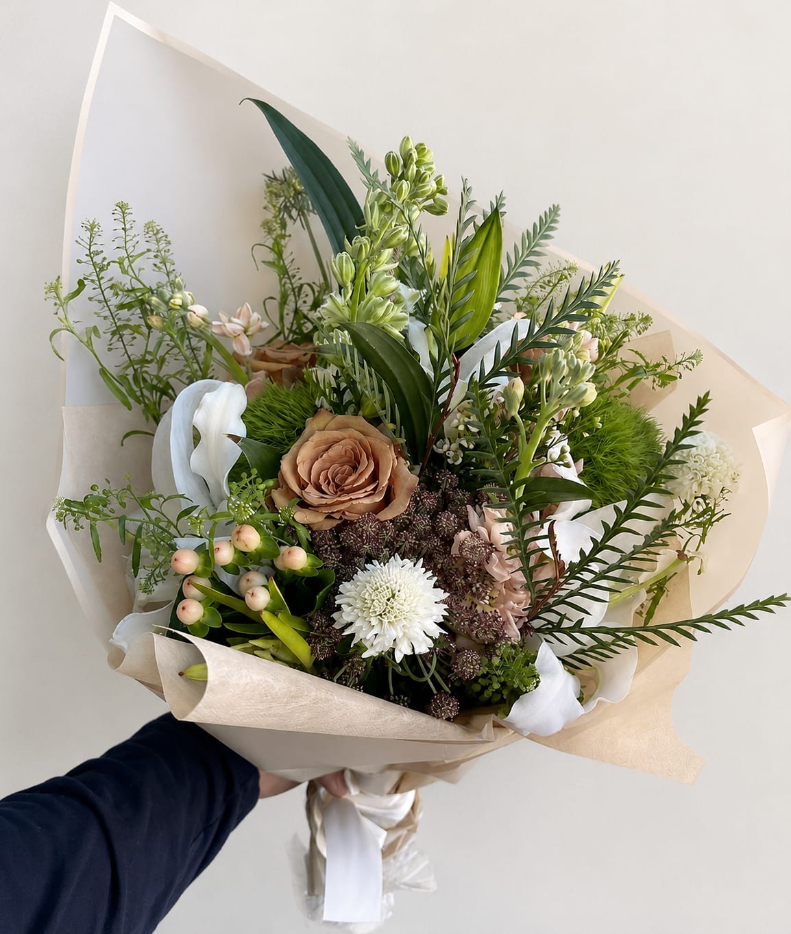 Hand-tied bouquet with tan, white, and pale pink flowers