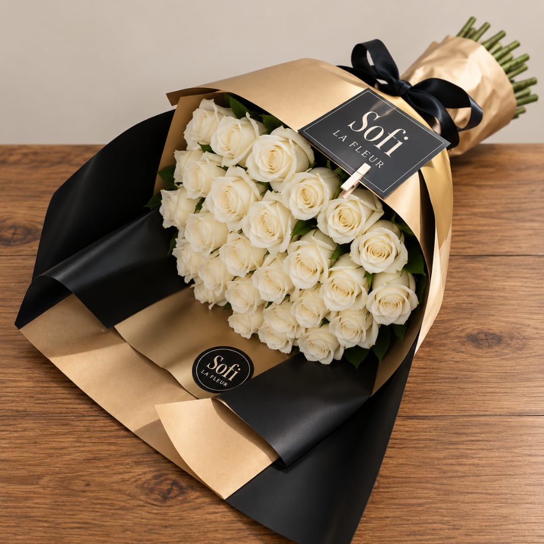 Bouquet of white roses wrapped in gold and black paper with a ribbon