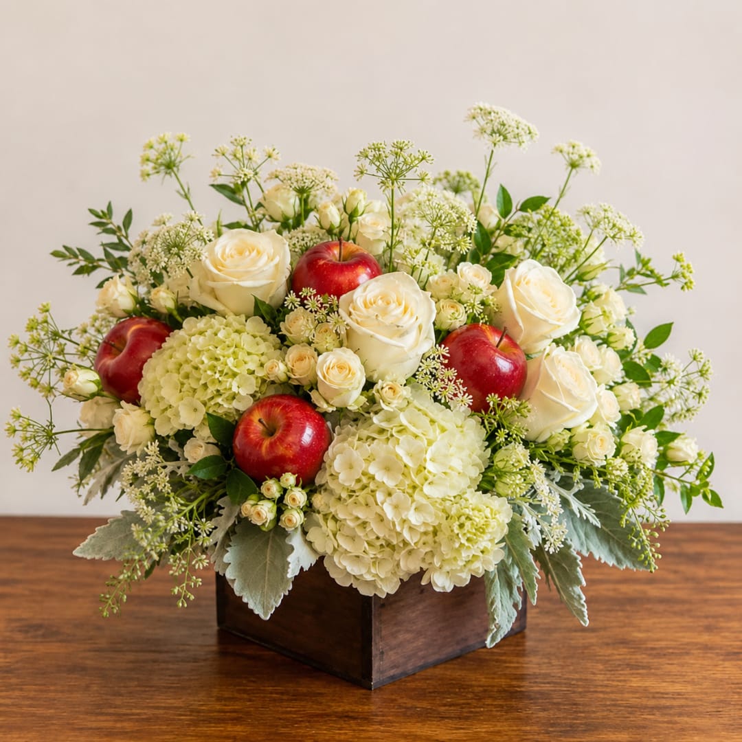 White roses and hydrangeas with red apples in a wooden box