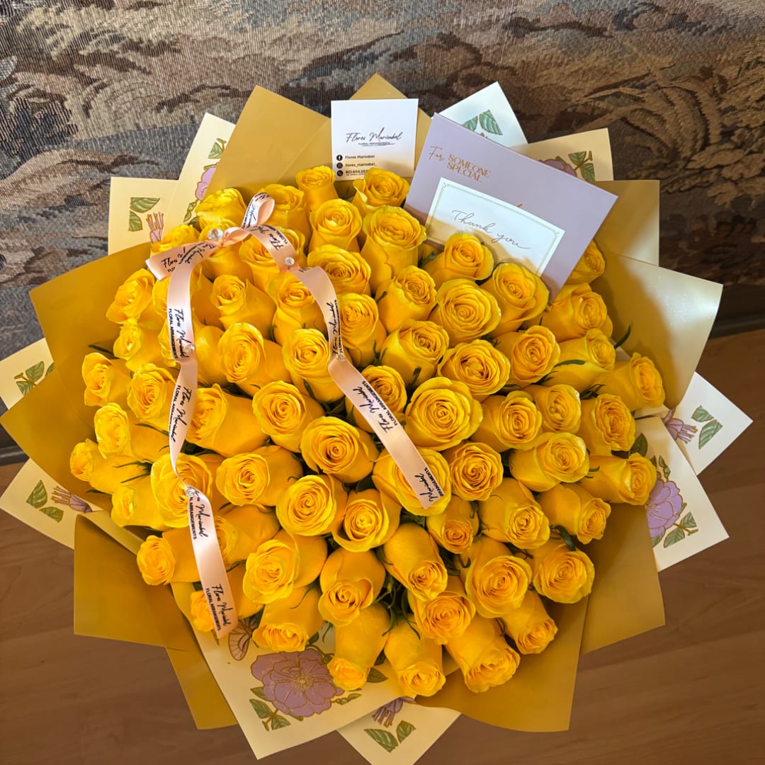 Large bouquet of yellow roses wrapped in gold paper with ribbon and cards