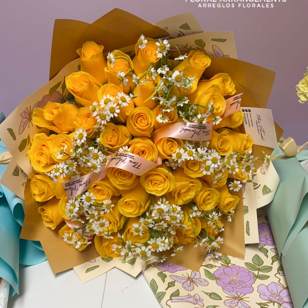 Bouquet of yellow roses with small white daisies wrapped in patterned paper