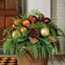 Holiday arrangement with pinecones and gold ornaments in a brown container