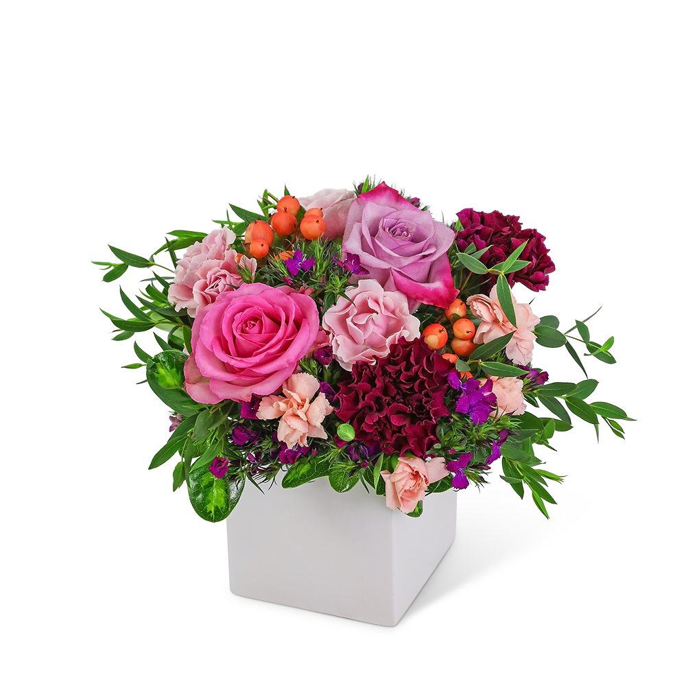Pink and purple rose arrangement in a white square vase