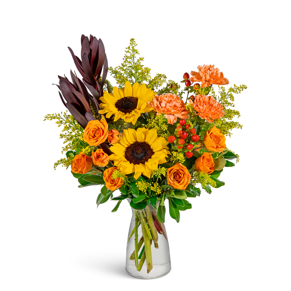 Bouquet of sunflowers, orange roses, and carnations in a clear glass vase
