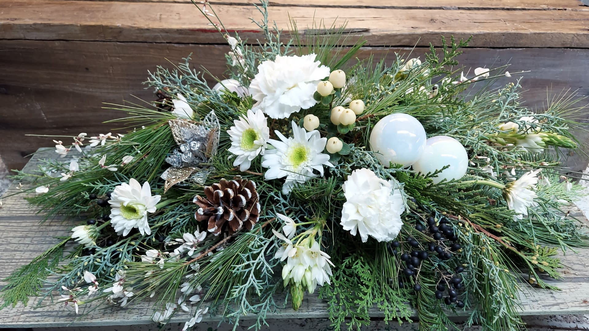 Low winter arrangement with white flowers, pinecones, and ornaments