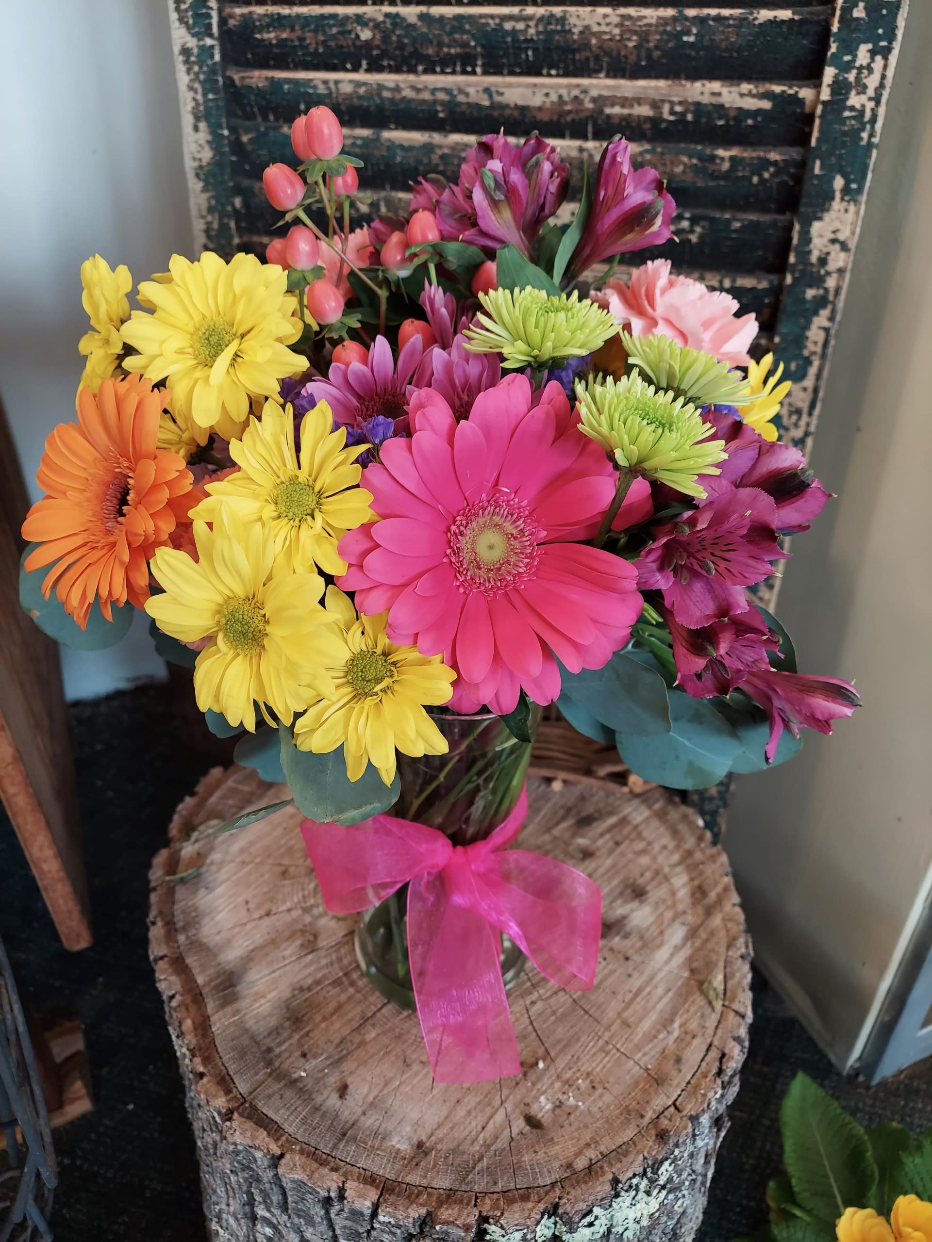 Colorful mixed bouquet in a glass vase with a pink ribbon