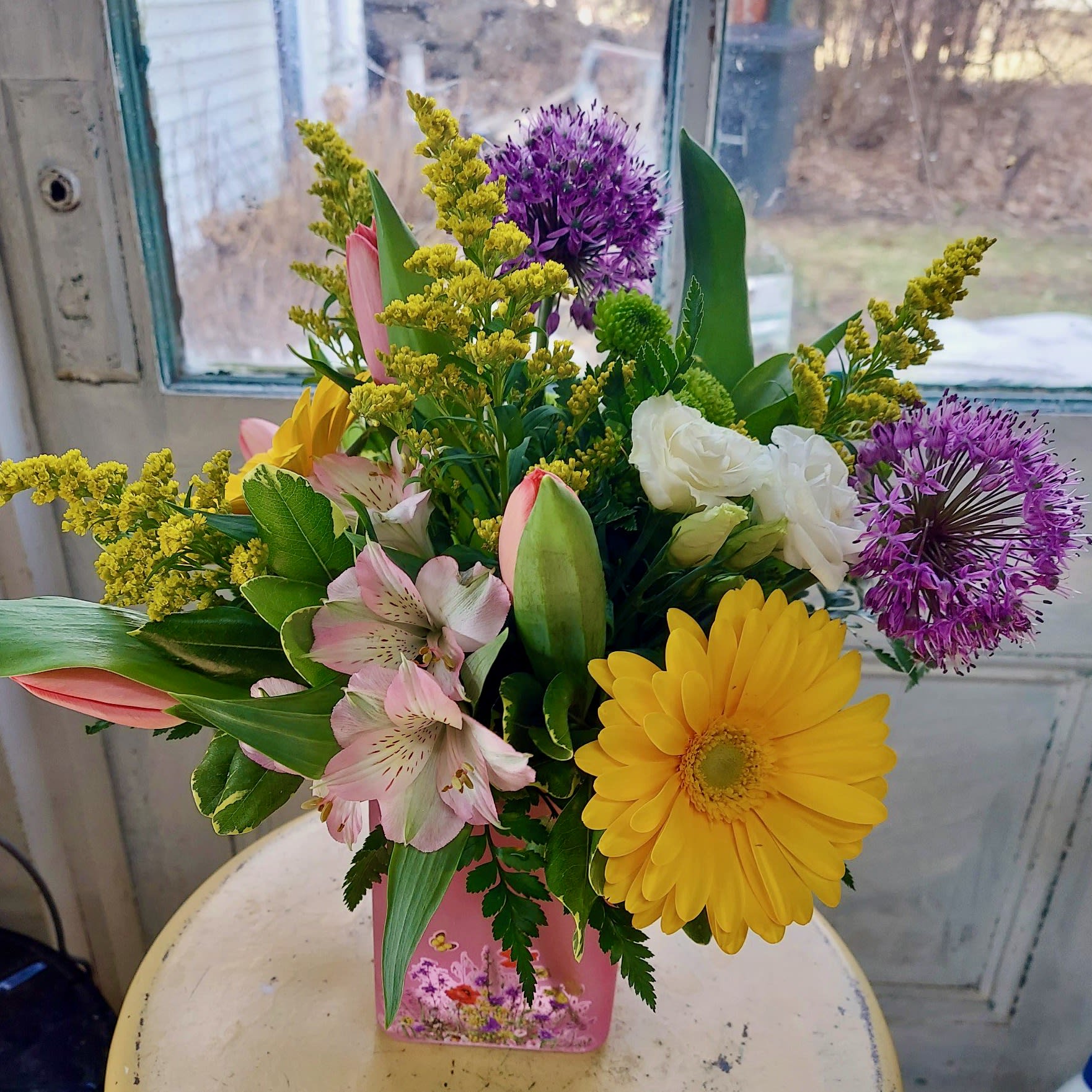 Mixed bouquet in a pink vase with yellow, purple, pink, and white flowers