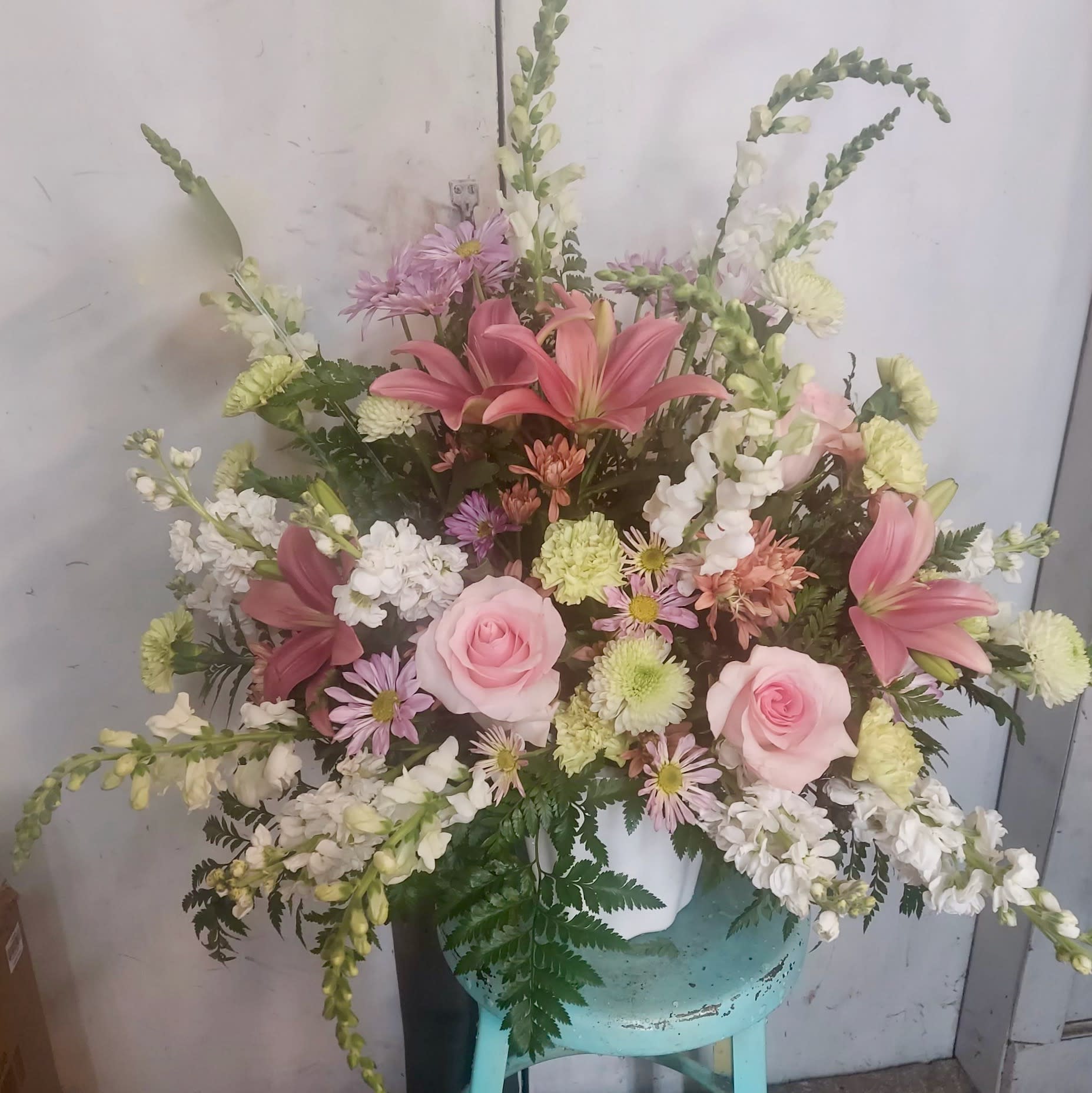 Pink roses and lilies in a white vase with white and lavender flowers