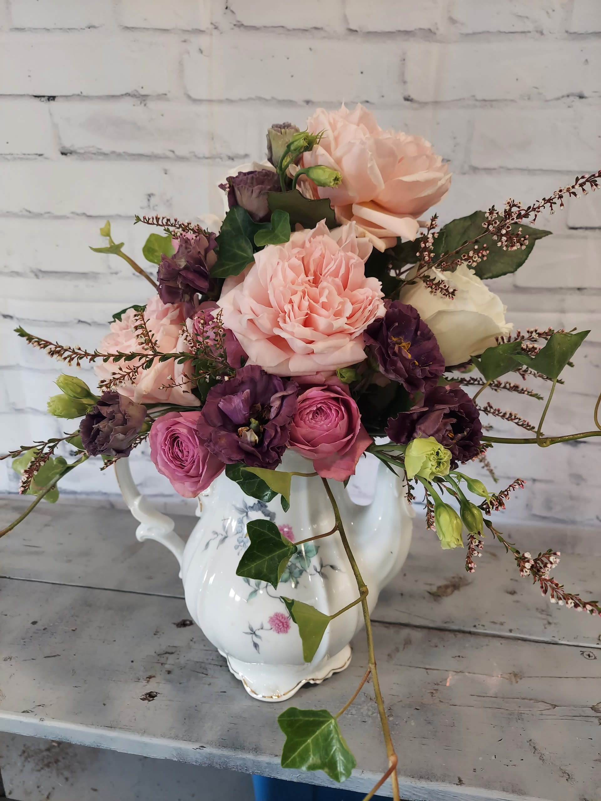 Pink and purple flowers arranged in a white porcelain vase