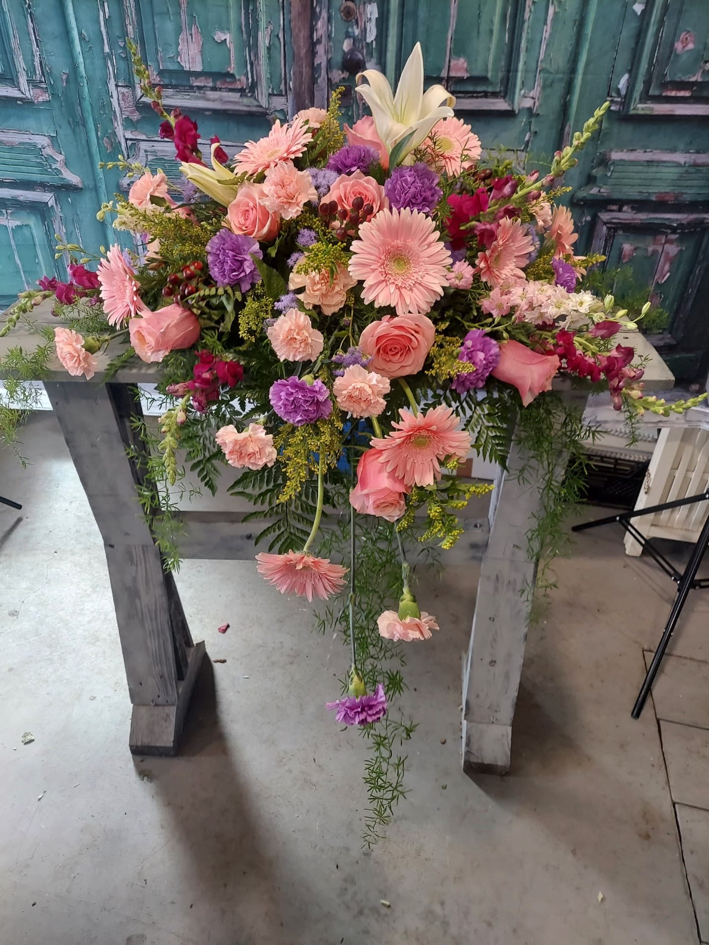 Large pink and purple floral arrangement on a wooden stand