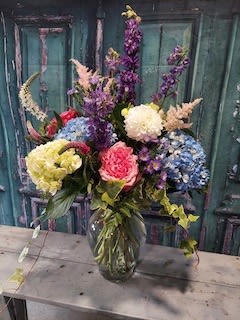 Colorful mixed bouquet in a glass vase with tall purple blooms