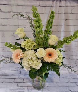 Mixed bouquet with pale roses, gerbera daisies, and hydrangeas in a glass vase