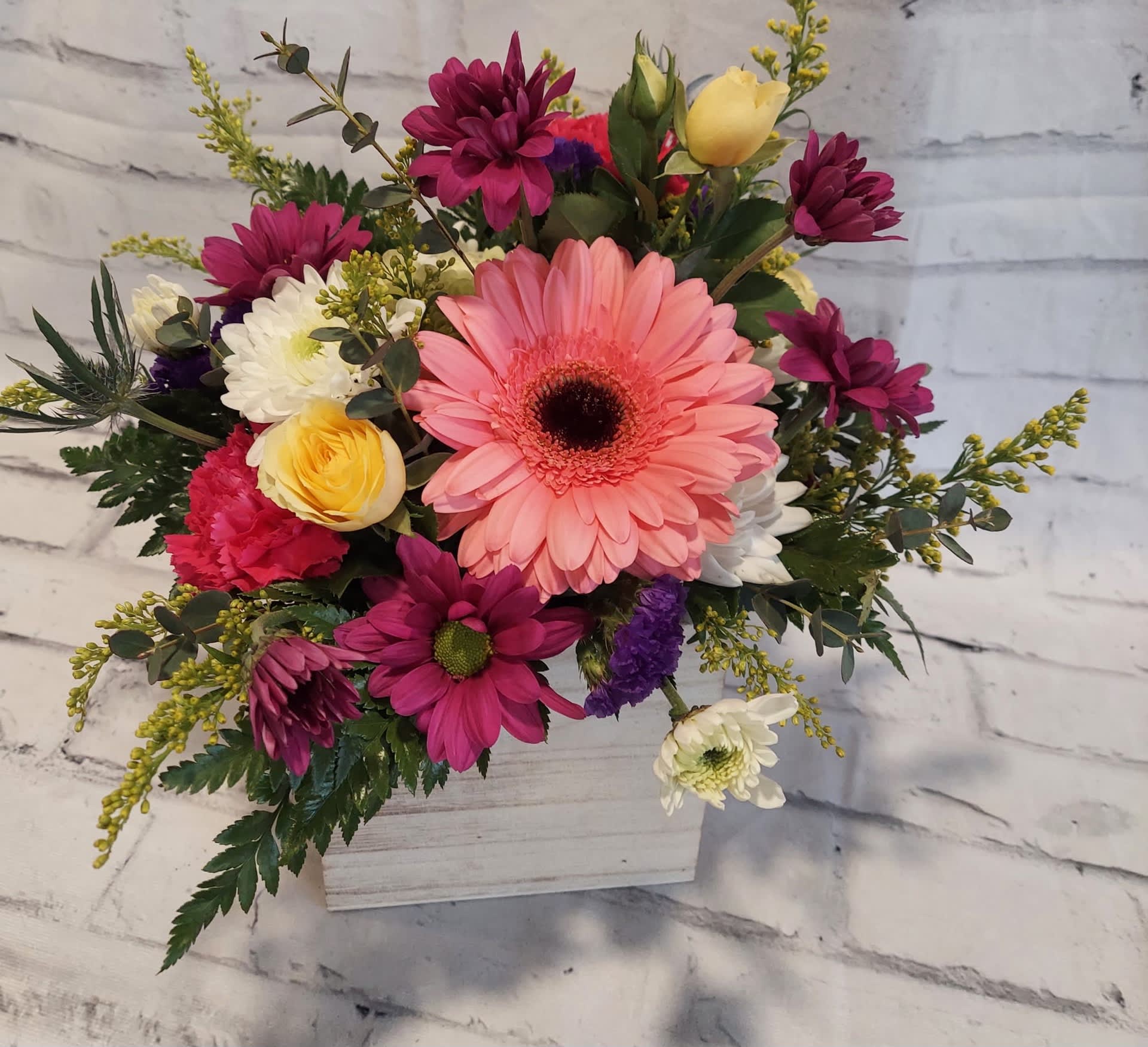 Mixed bouquet in a white wooden box with pink, yellow, and white flowers
