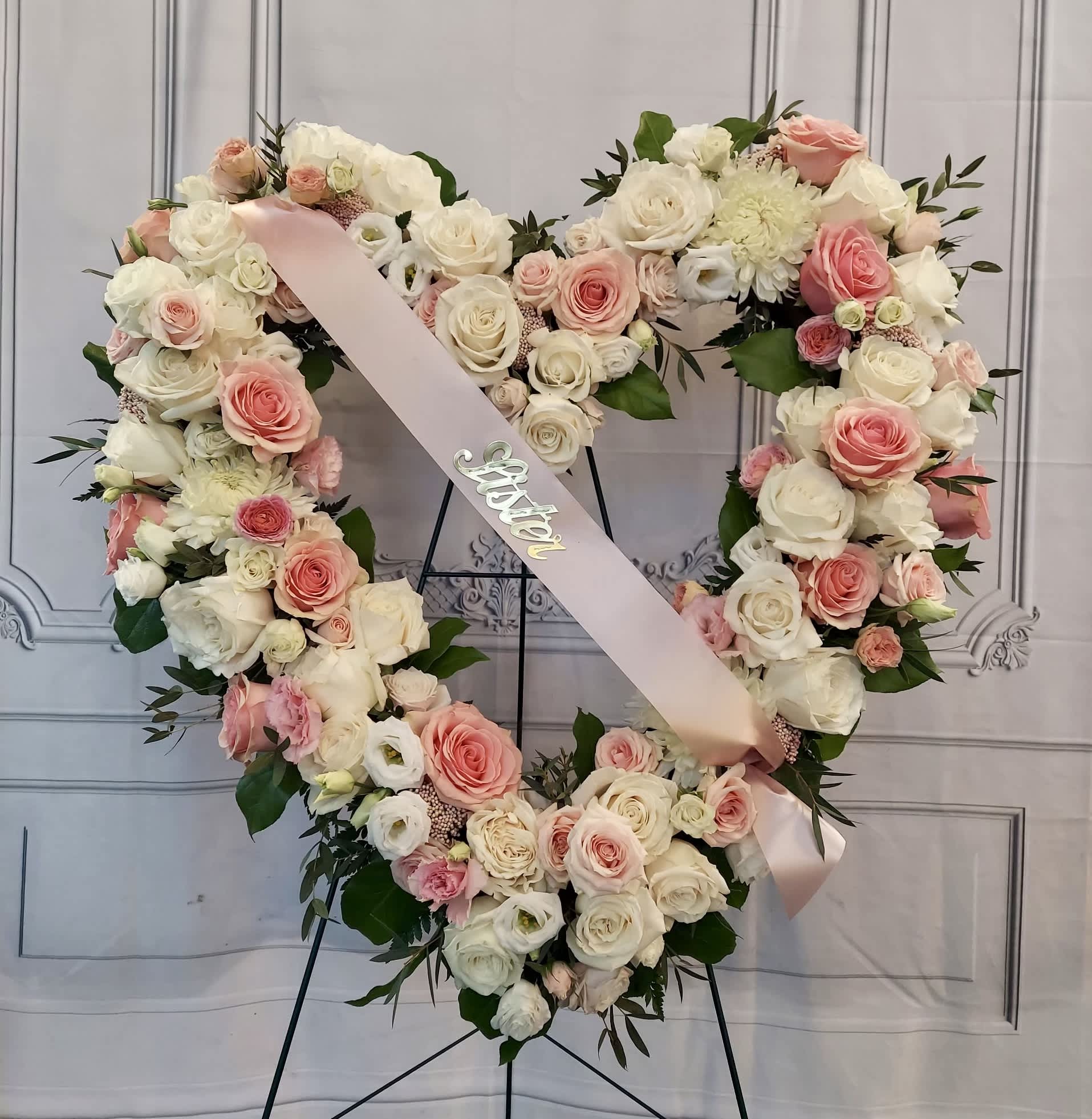 Heart-shaped floral wreath of pink and white roses with a pink ribbon